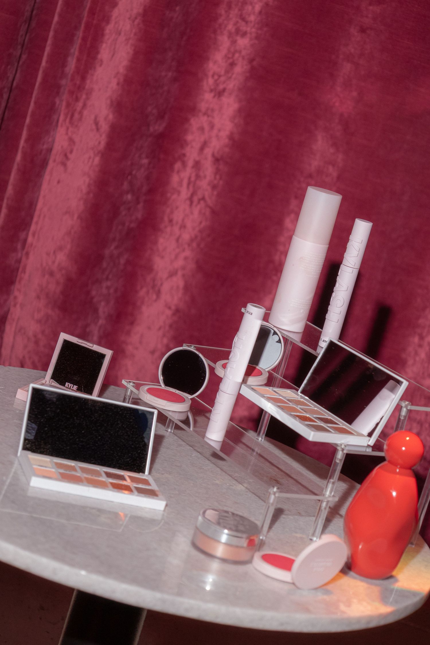 White and orange objects arranged on a reflective surface with dramatic burgundy lighting and shadows.