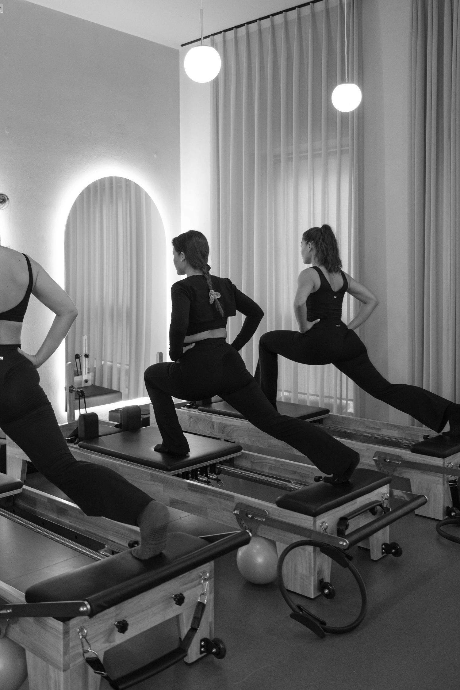 Black and white sequence of Pilates reformer exercises being performed in a studio.