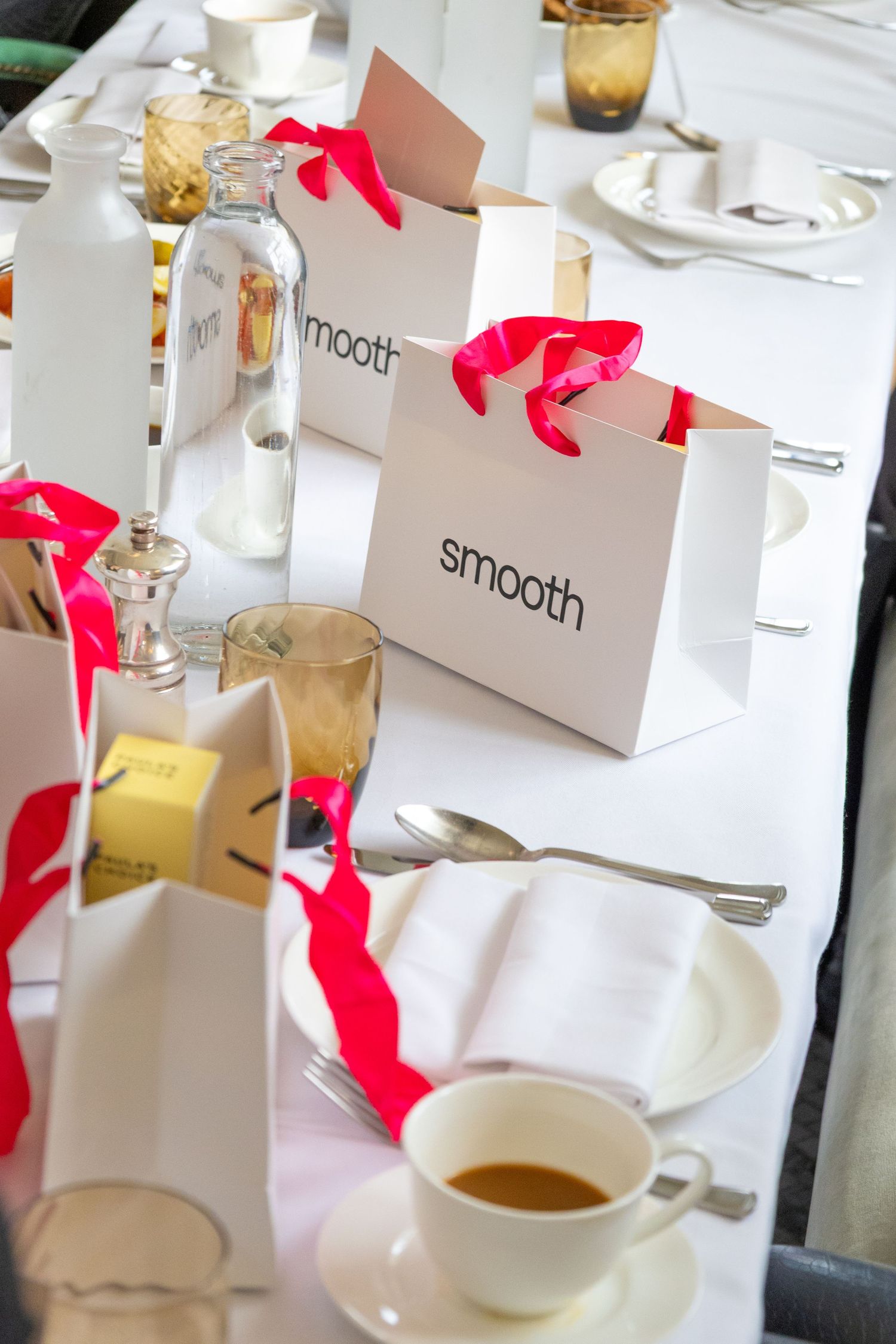 Elegant table setting with white place cards, amber glassware, and bright red decorative accents at a restaurant.