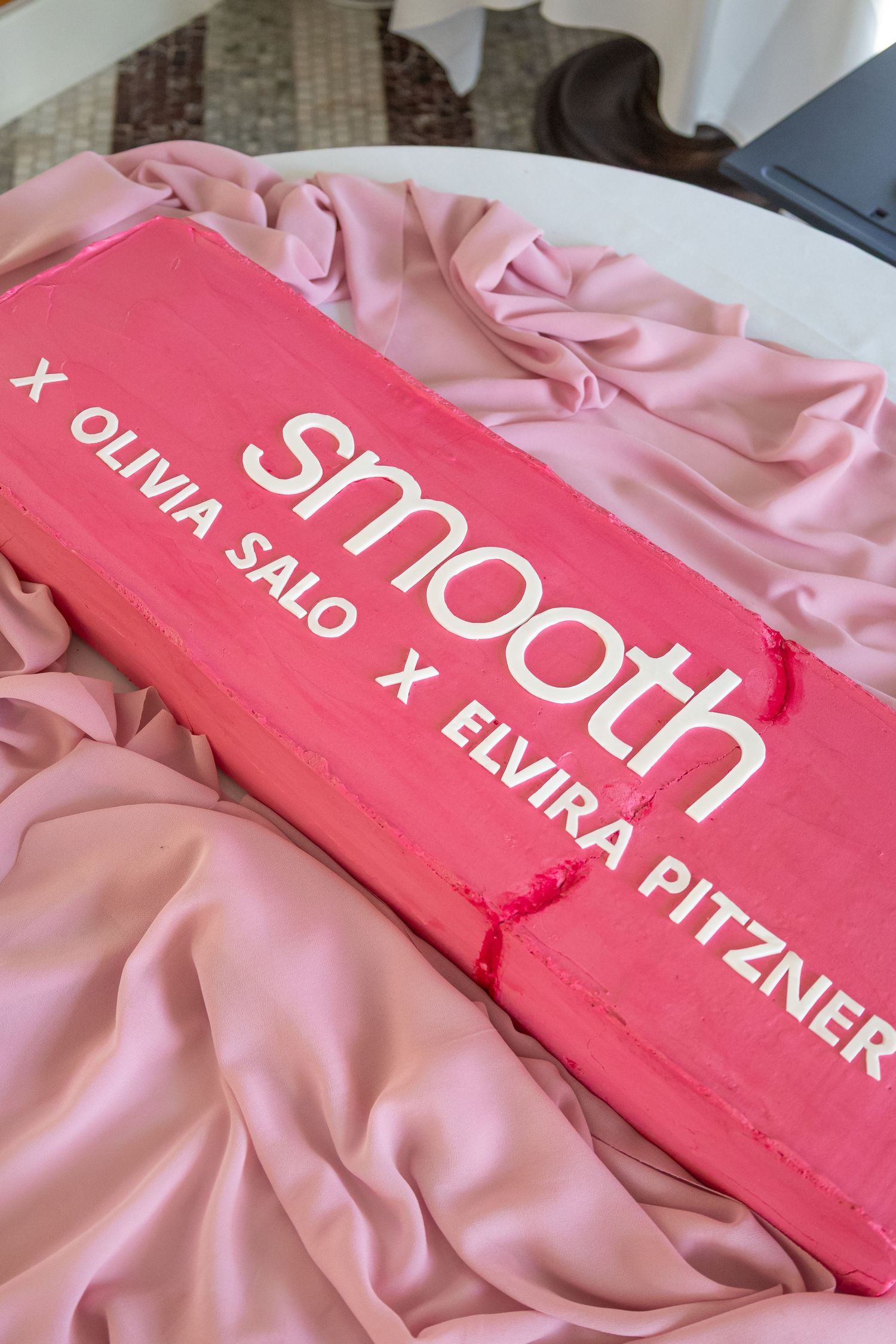 Close-up of pink fabric with text overlay showing branding elements.