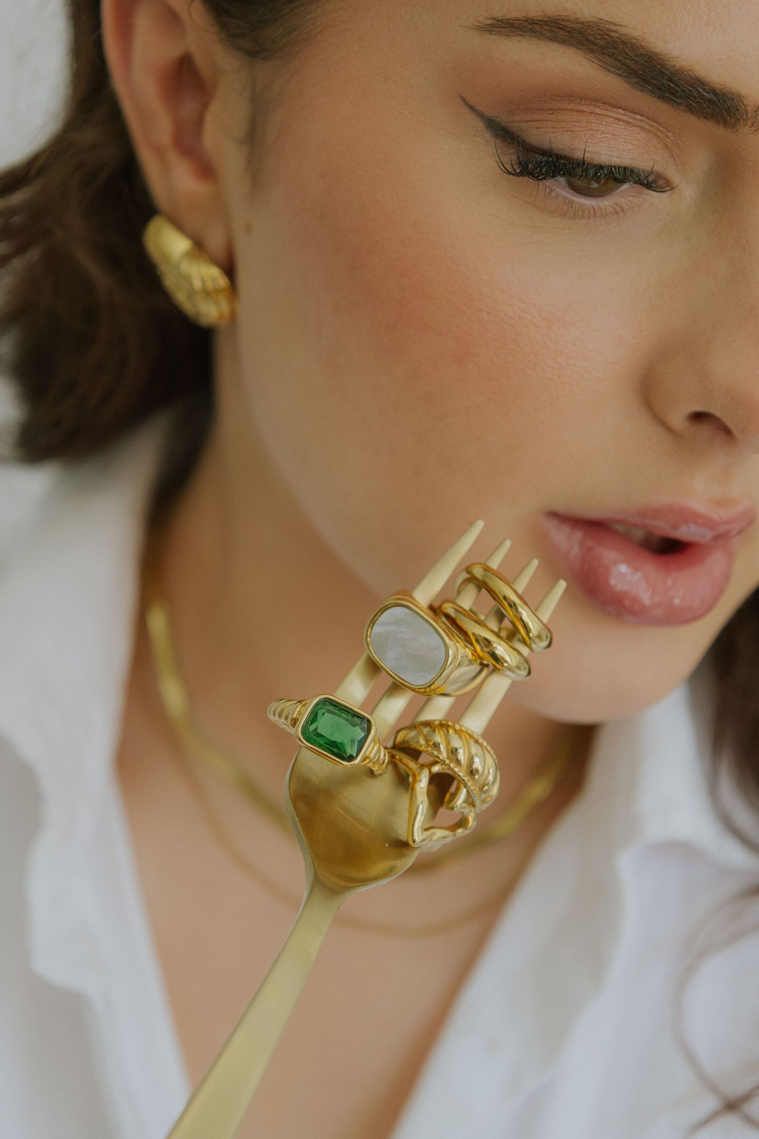 Close-up shots of gold jewelry with gemstones against neutral background.