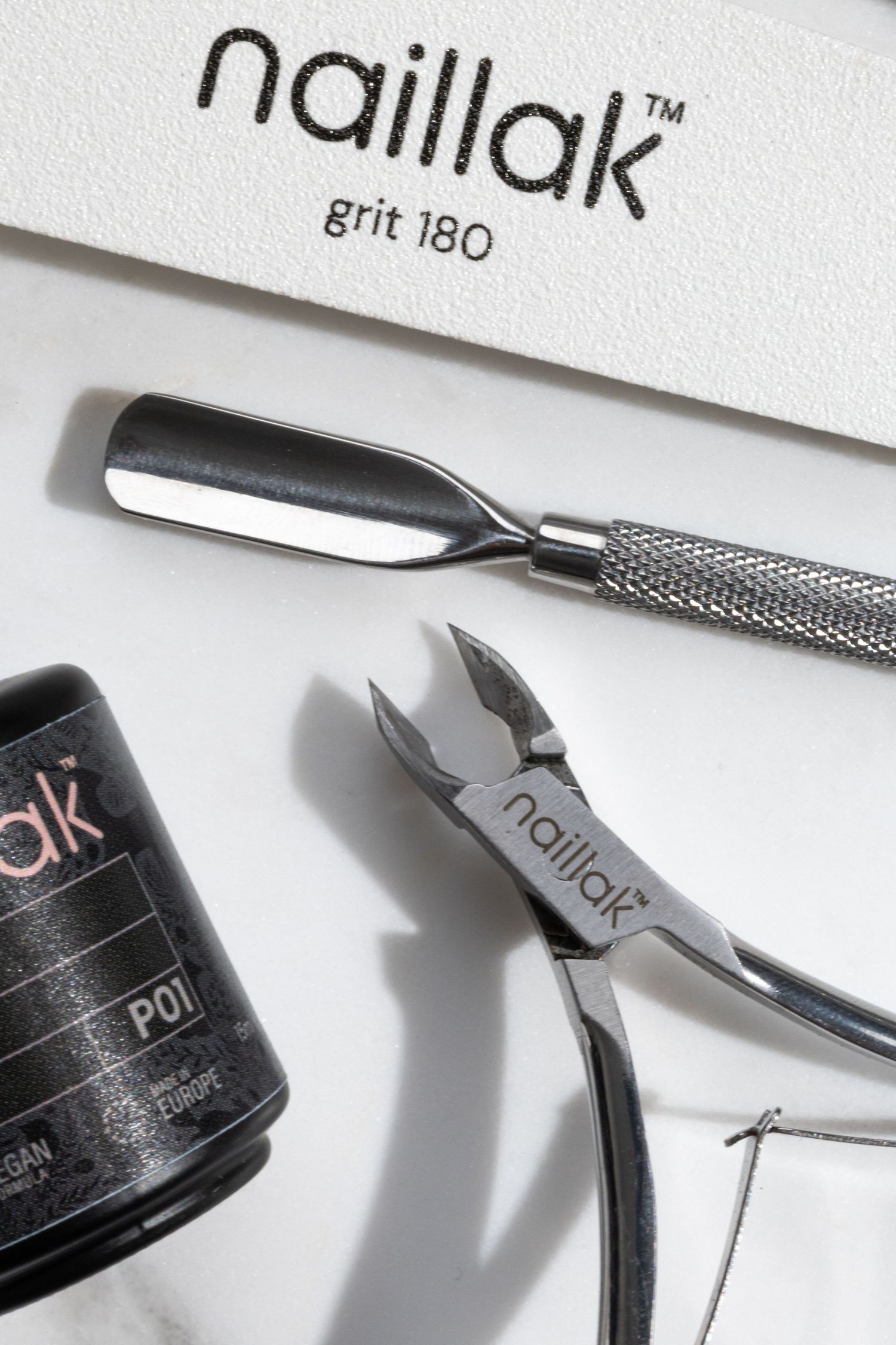 Close-up of nail care tools and products with text labels against white background.