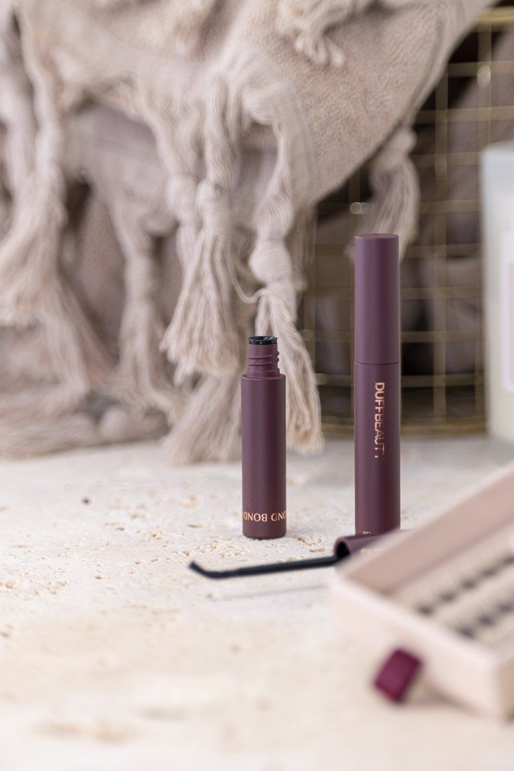 Purple cosmetic product bottles displayed against textured background.
