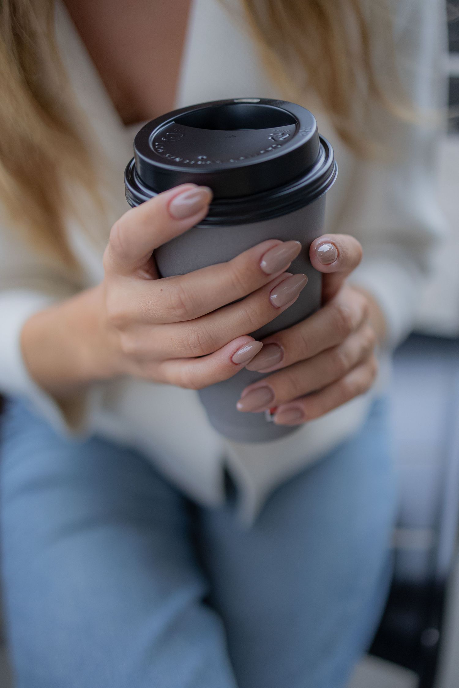 Hands holding a dark coffee cup with blurred background.