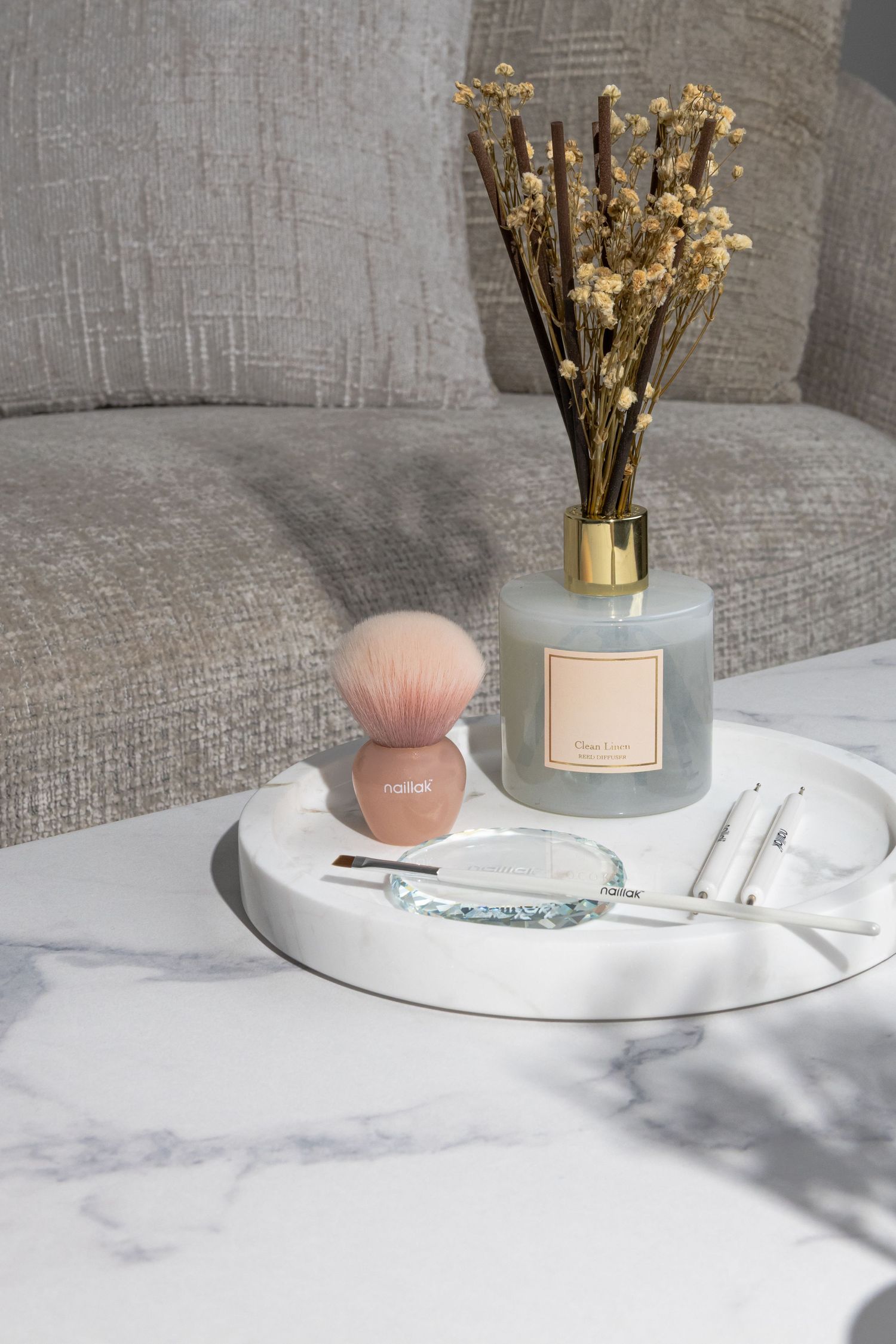 Minimalist display of dried flowers and candles on marble surface with soft lighting.