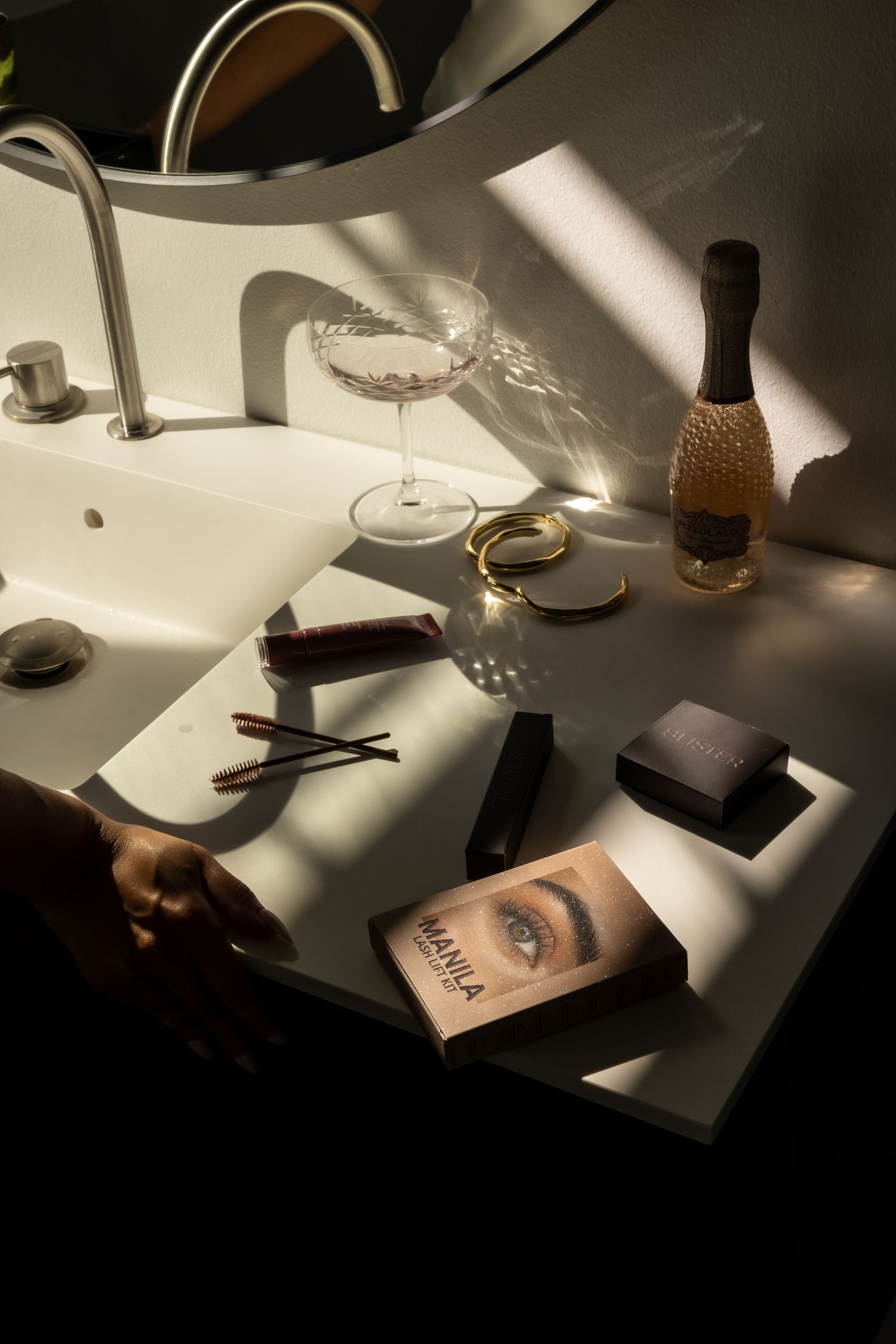 Moody still life photography of beauty products and accessories on white surface with dramatic lighting.