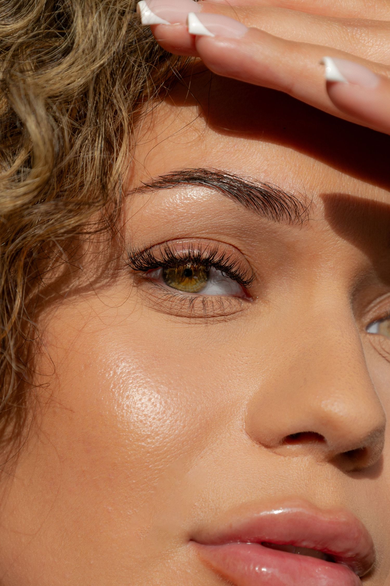 Close-up beauty shot showing glowing skin and defined eyebrow in natural sunlight.