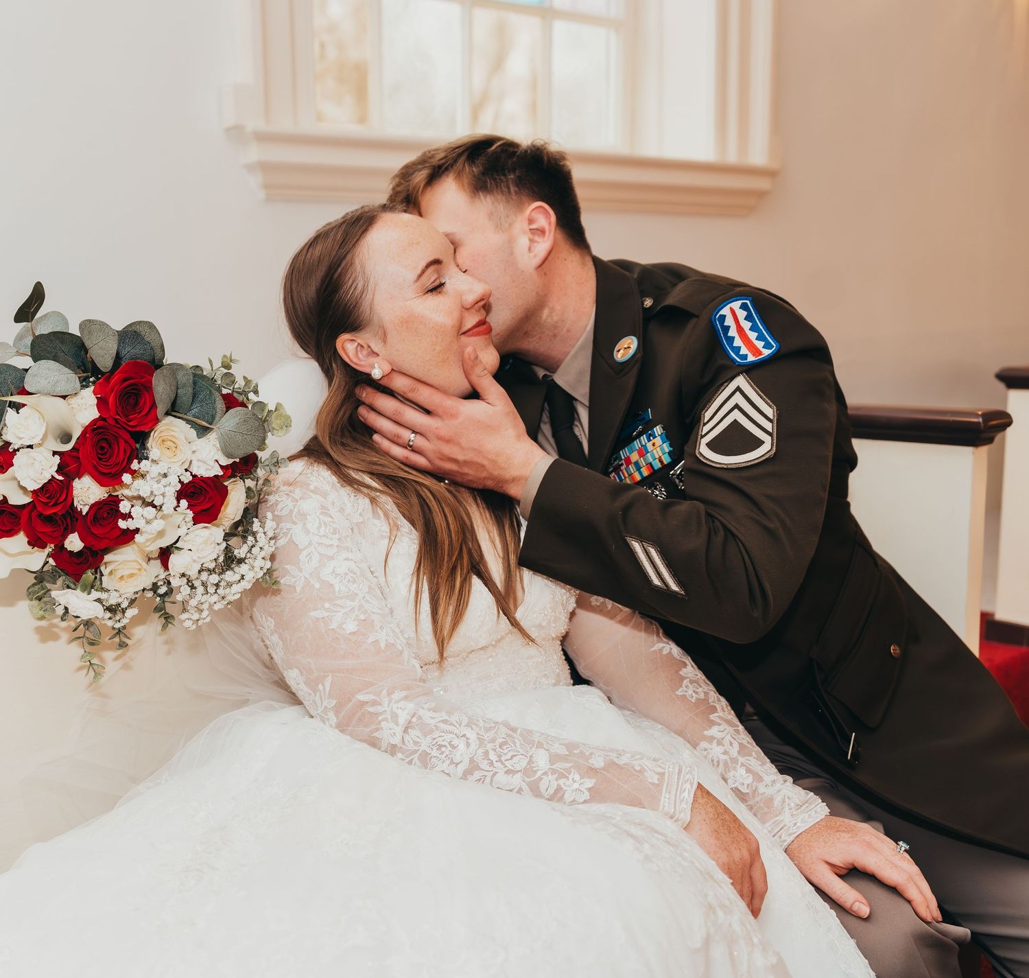 Intimate wedding moment in formal military dress and lace gown by window.