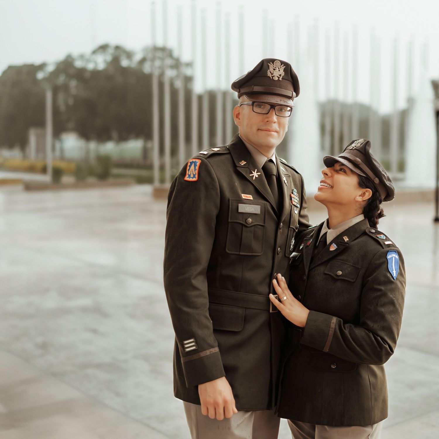 Two people in military uniforms sharing an intimate moment outdoors.
