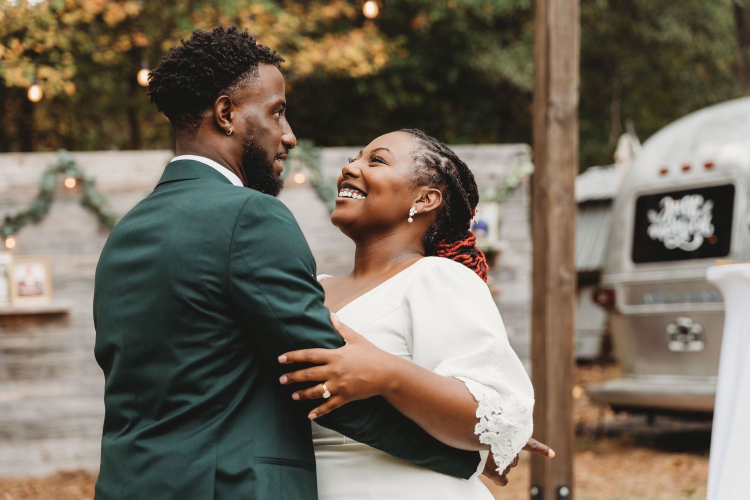 Two people sharing a joyful moment during their outdoor wedding celebration.