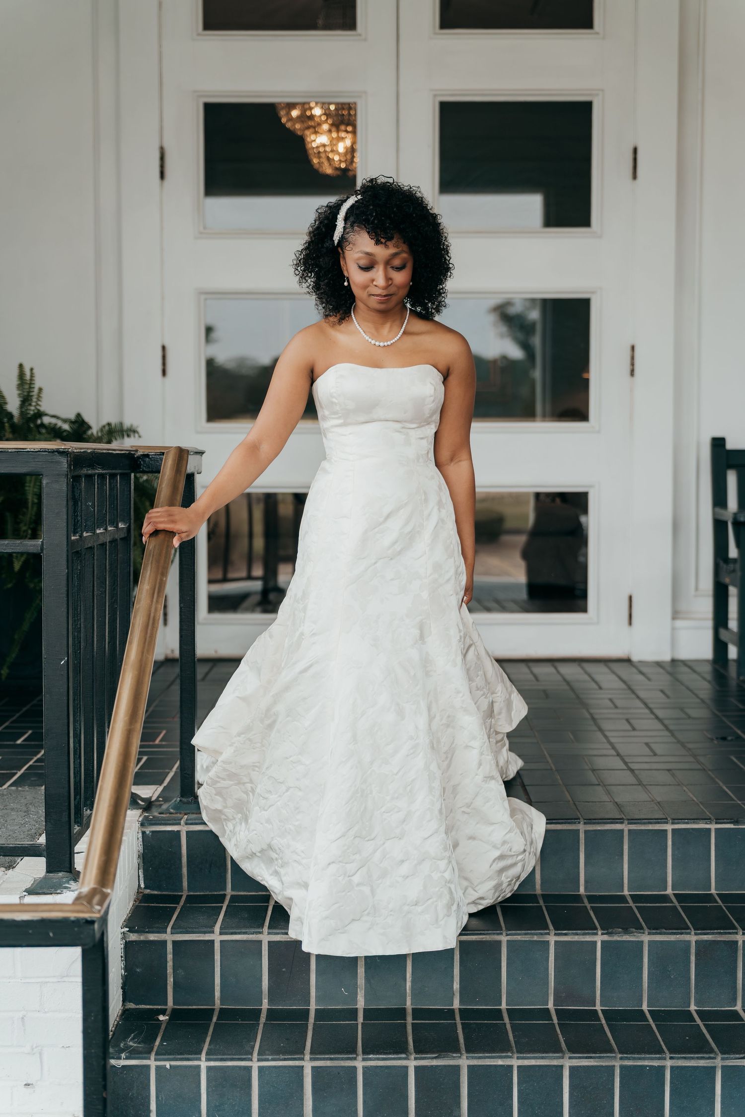 A beautiful strapless white wedding gown with lace detail on stone steps.