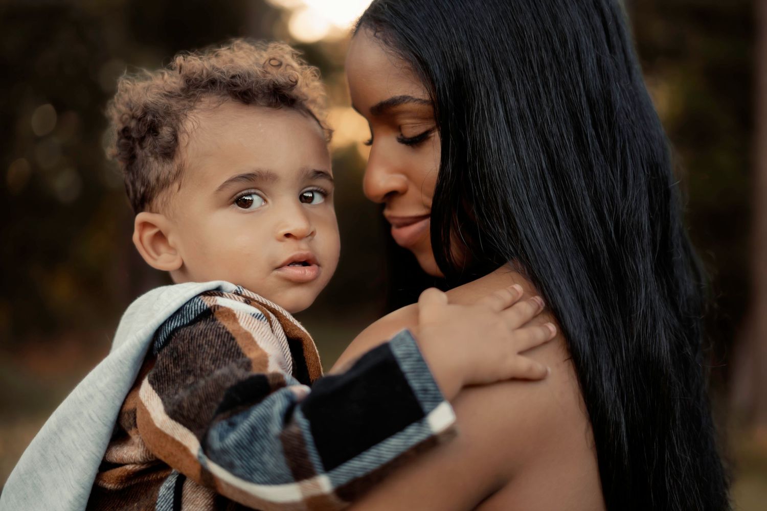 Intimate mother and child portrait in warm natural lighting outdoors.
