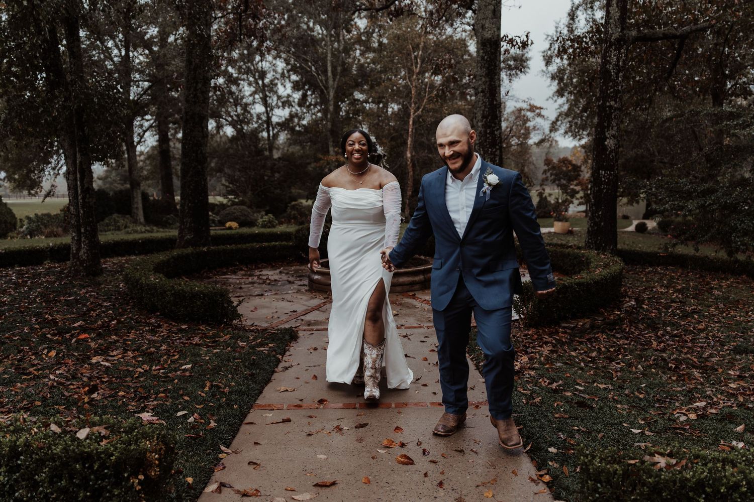 A couple walking along an autumn garden path during their wedding.