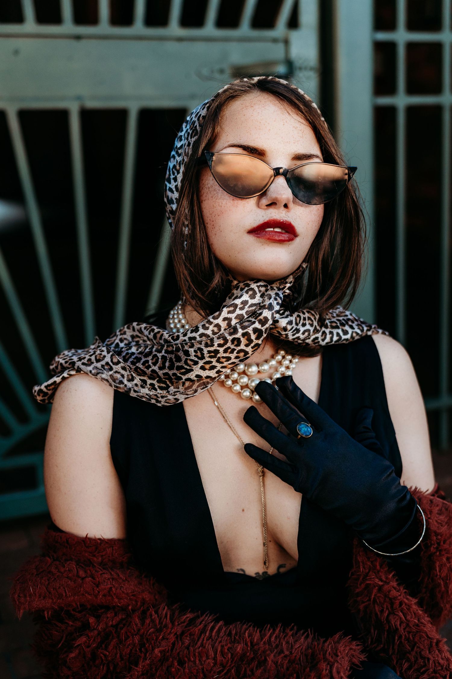 Portrait with leopard print scarf, black gloves, sunglasses and red lipstick in dramatic vintage glamour style.