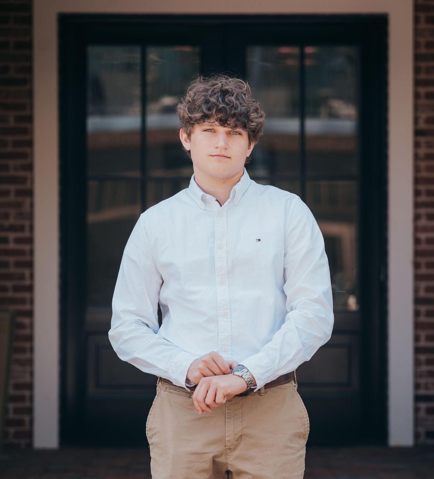 Portrait of person in white button-down shirt against dark doorway.