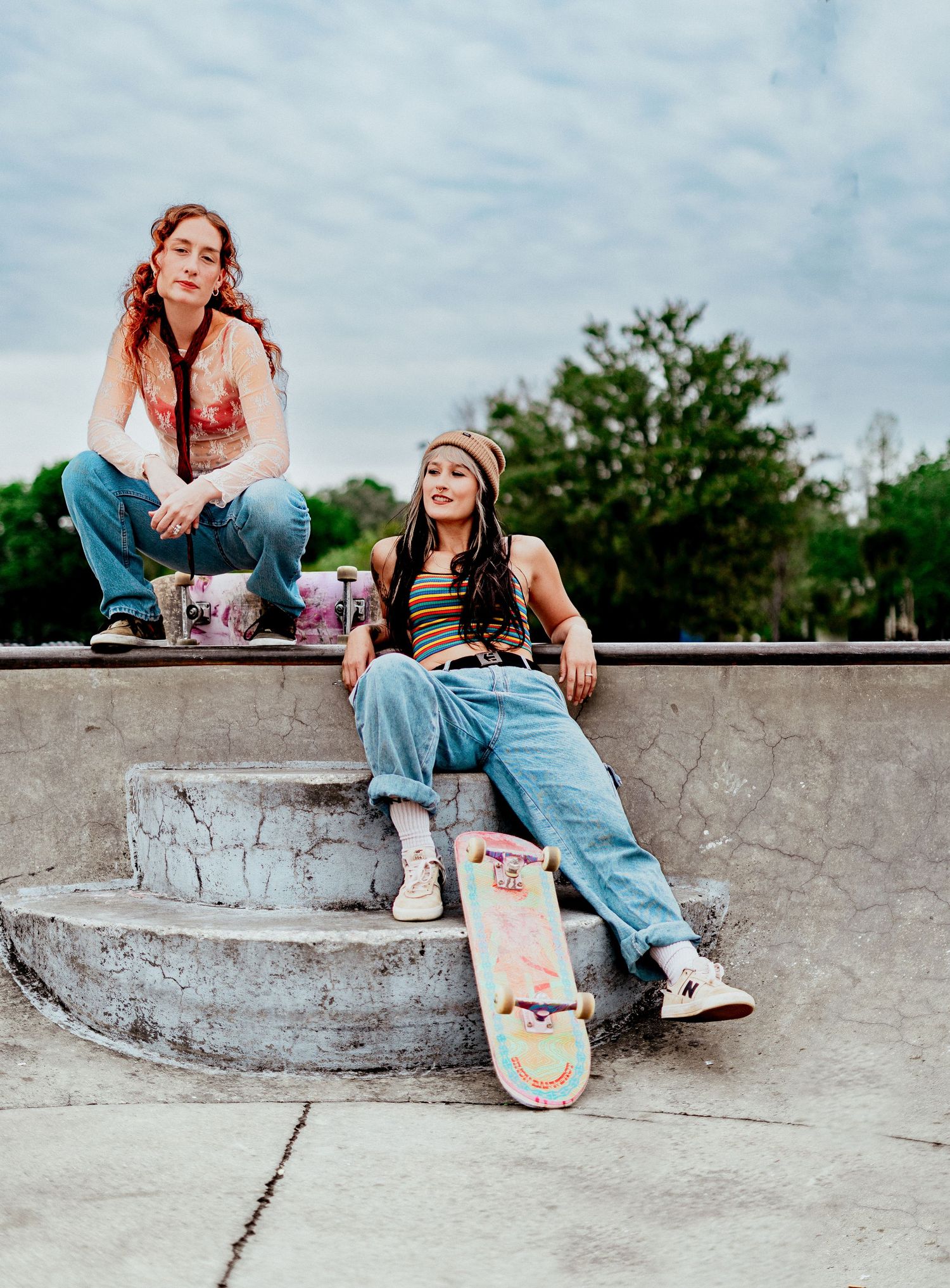 Two skateboarders sit on a concrete ledge having an animated conversation at golden hour.