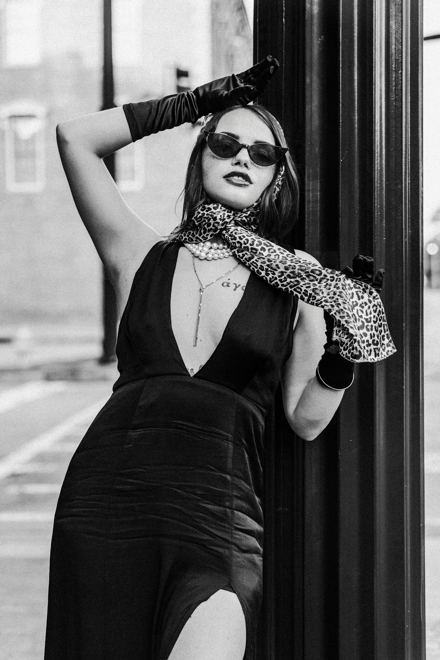 Black and white fashion portrait featuring retro styling with leopard print scarf, sunglasses and black evening dress.