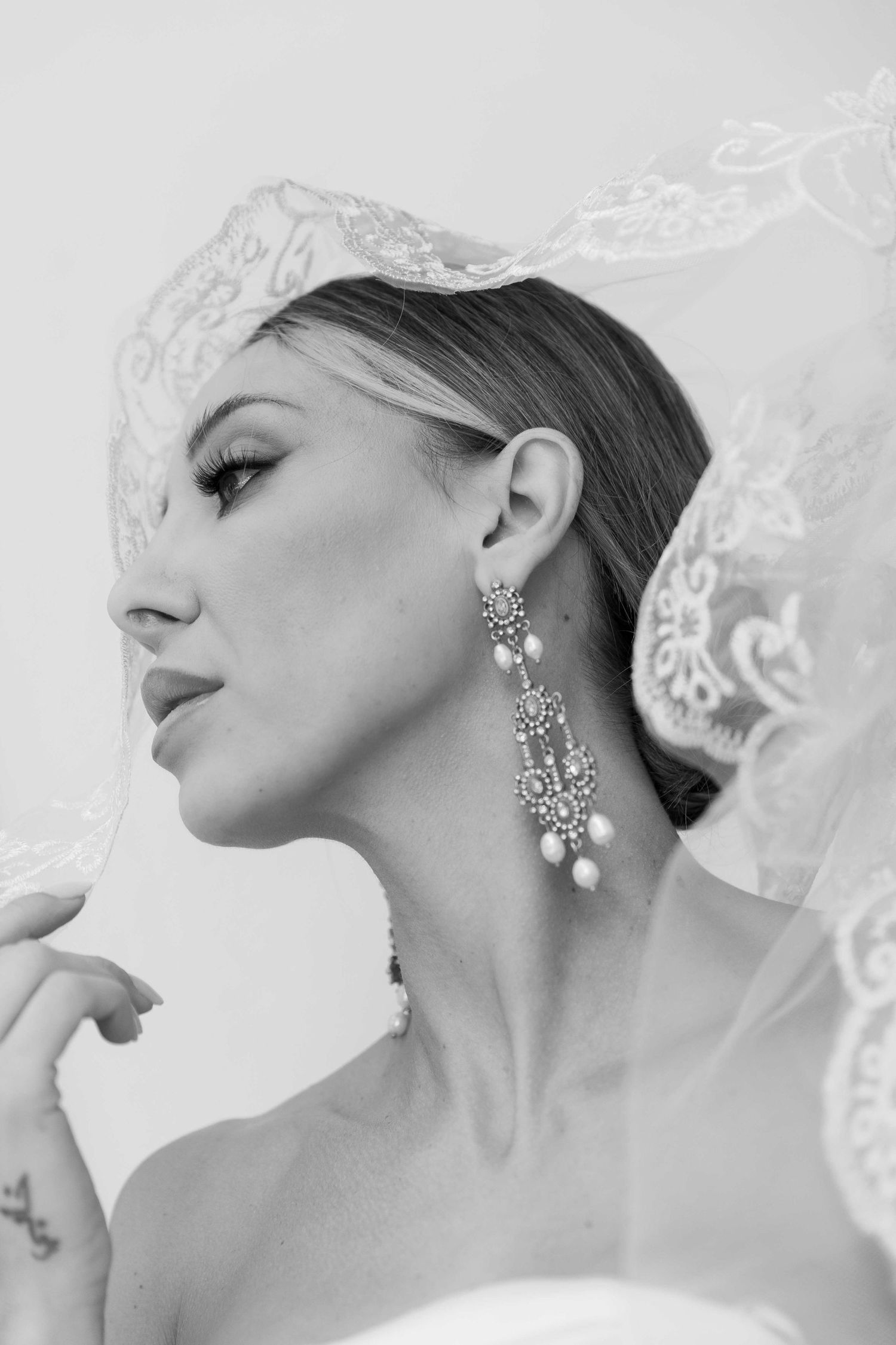 A series of black and white close-up photos showcasing elegant crystal drop earrings and delicate lace details.