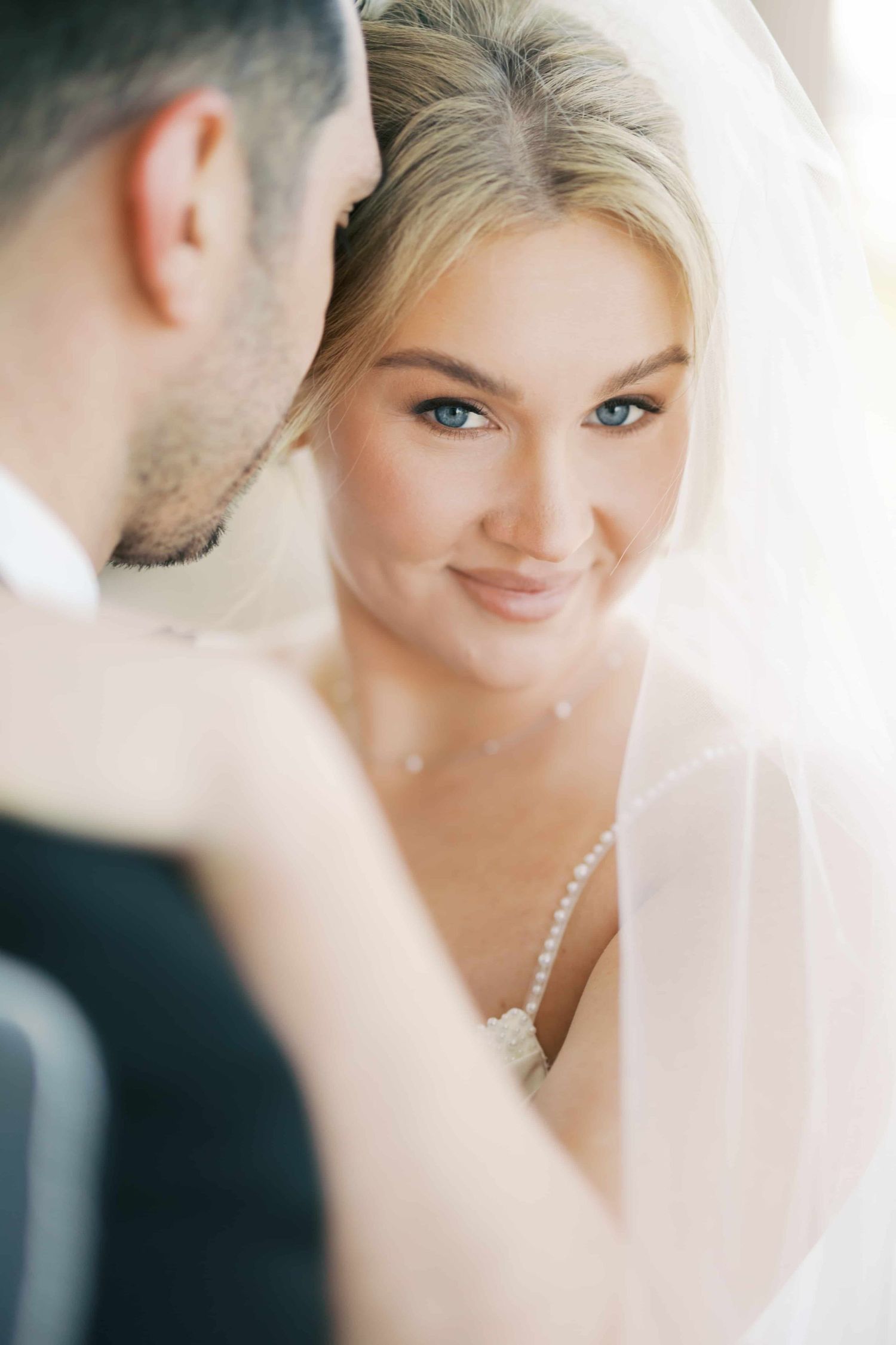 Intimate wedding portrait showing tender moment between bride and groom through delicate veil.