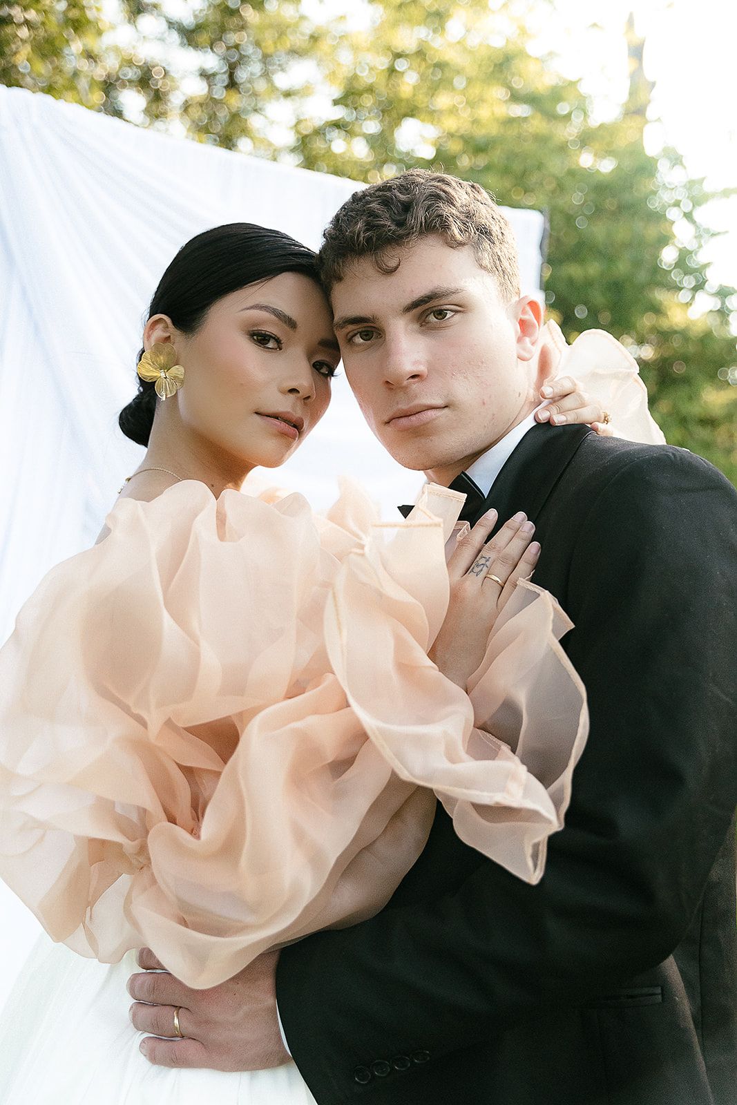 Artistic wedding portraits series showing intimate moments with soft peach colored bridal gown against dark suit.