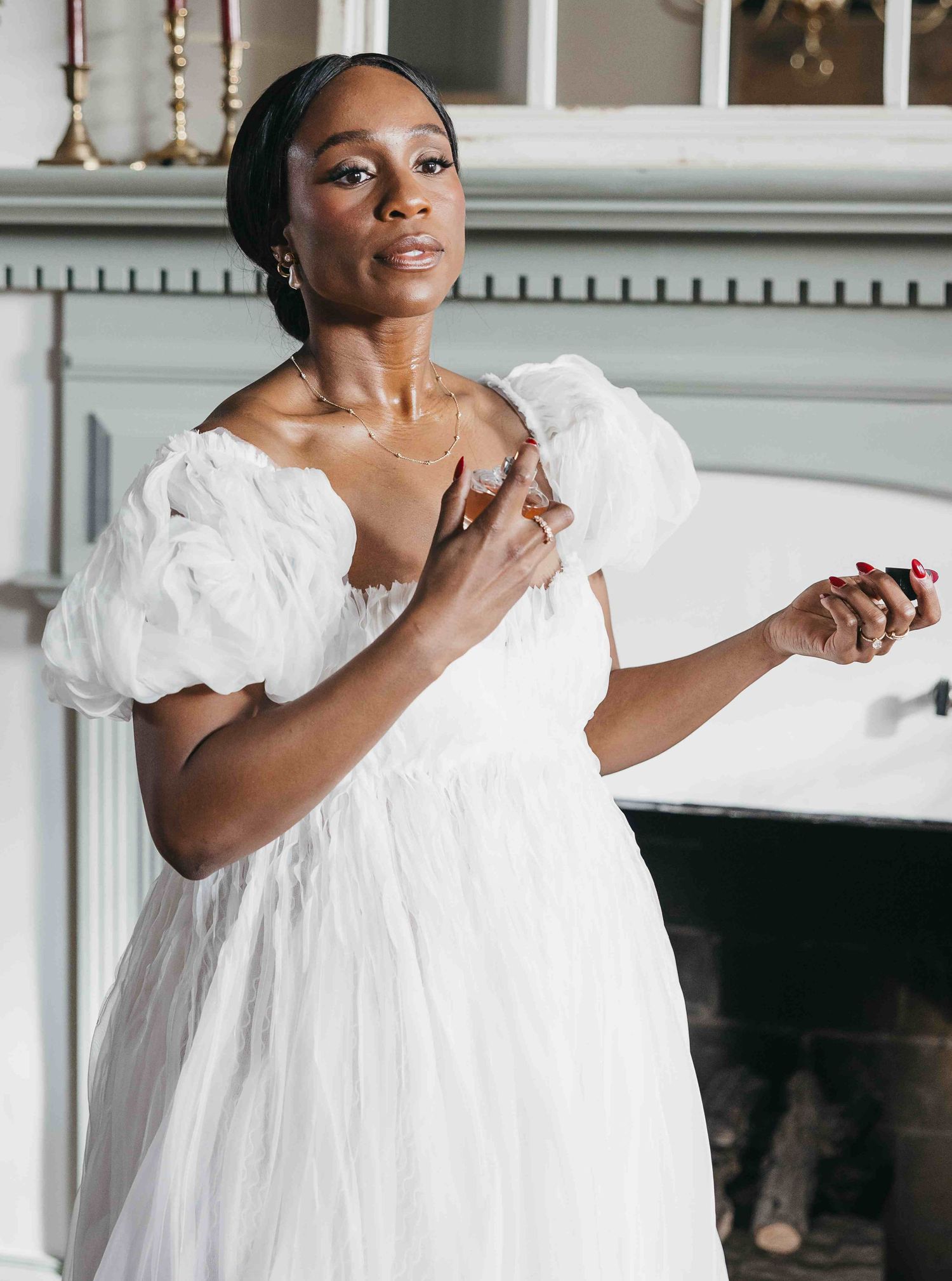 A bride in a romantic white puff-sleeve wedding dress poses in an elegant indoor setting.