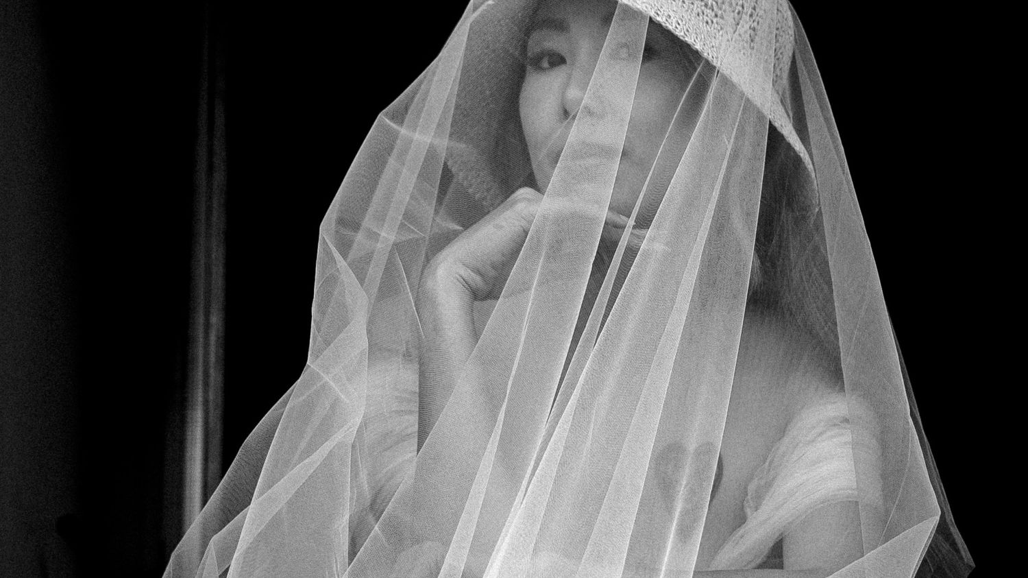 A sequence of five black and white photos showing a bride putting on her wedding veil in elegant detail.
