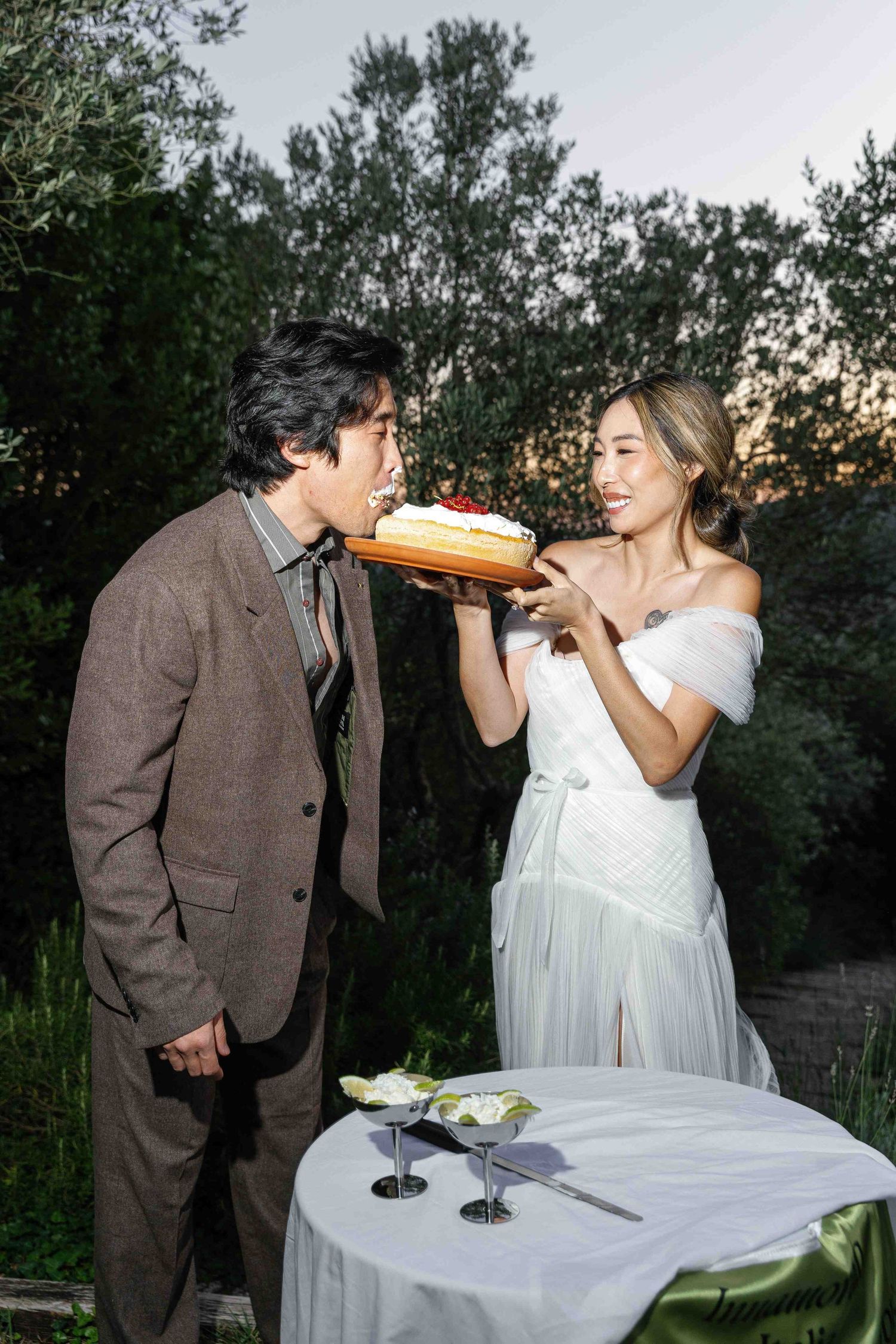 A playful moment of two people sharing a drink at an outdoor table during sunset.