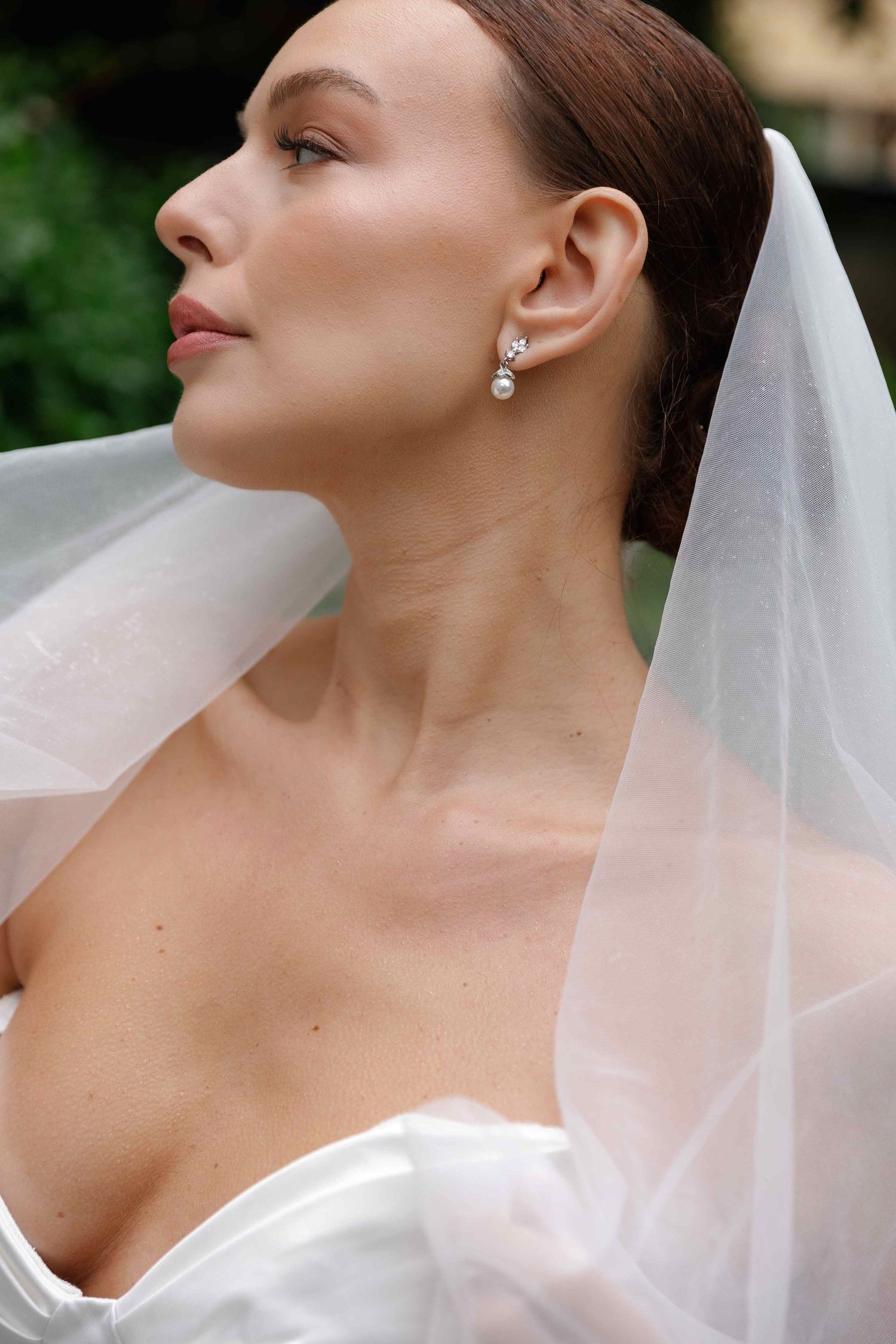 Close-up profile shots of bride wearing classic white wedding dress and veil with delicate jewelry.