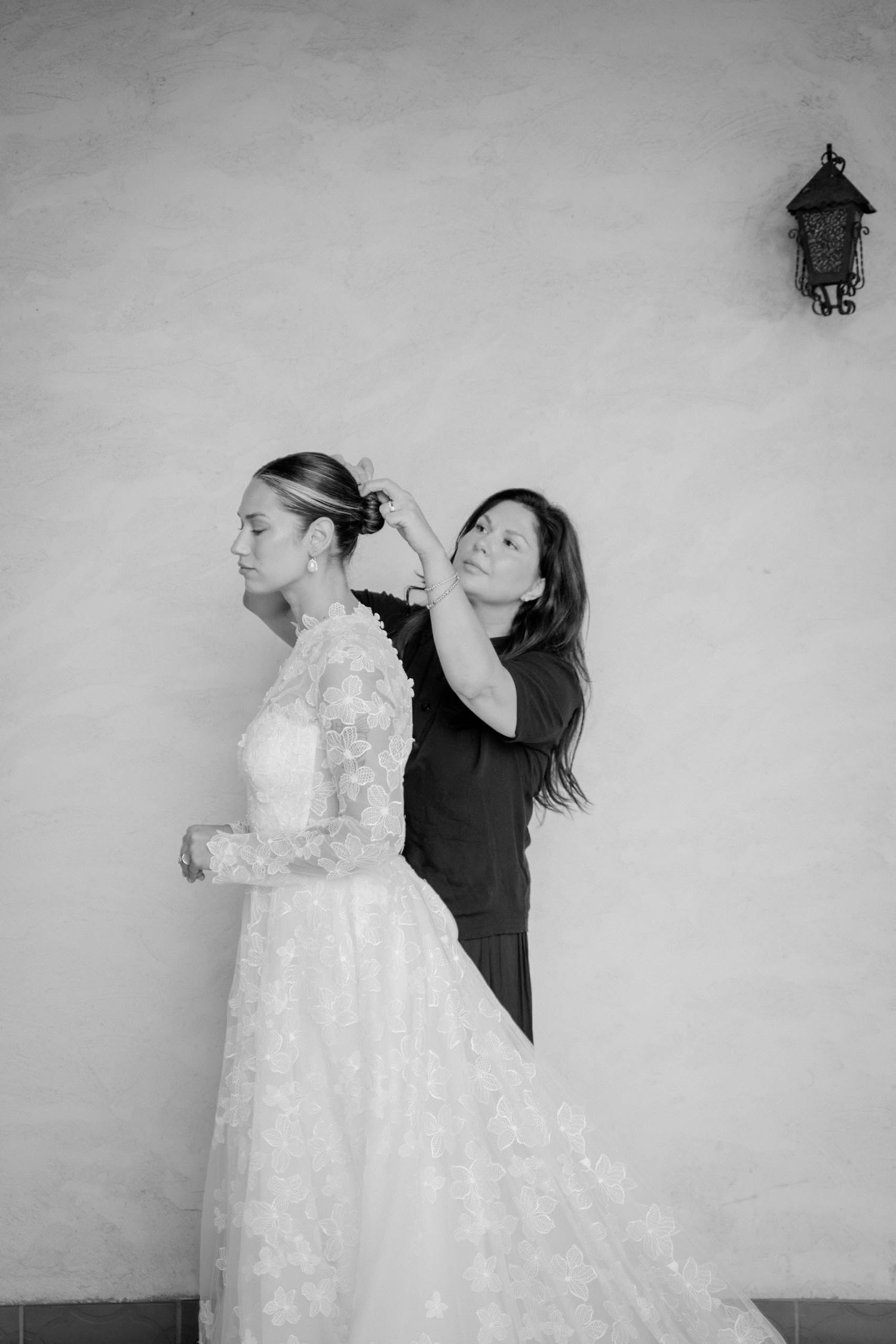 A series of black and white photos showing a person interacting with a white lace wedding dress hanging on a wall.