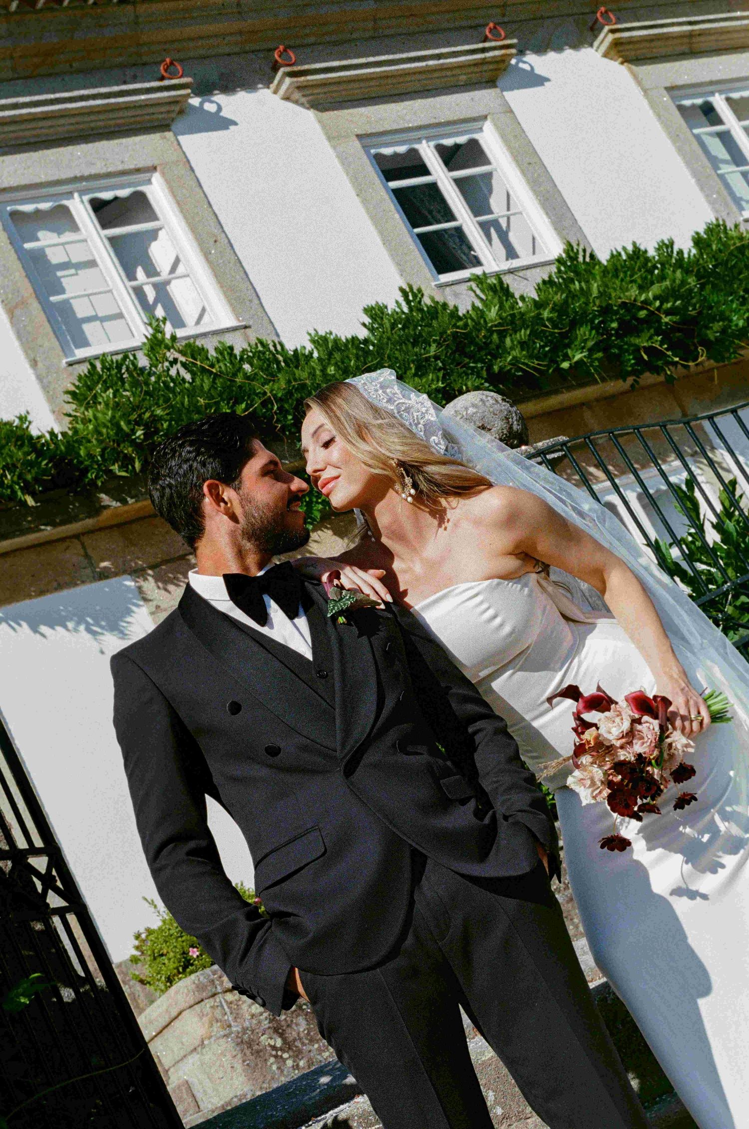 Wedding couple in formal attire sharing intimate moments outdoors.