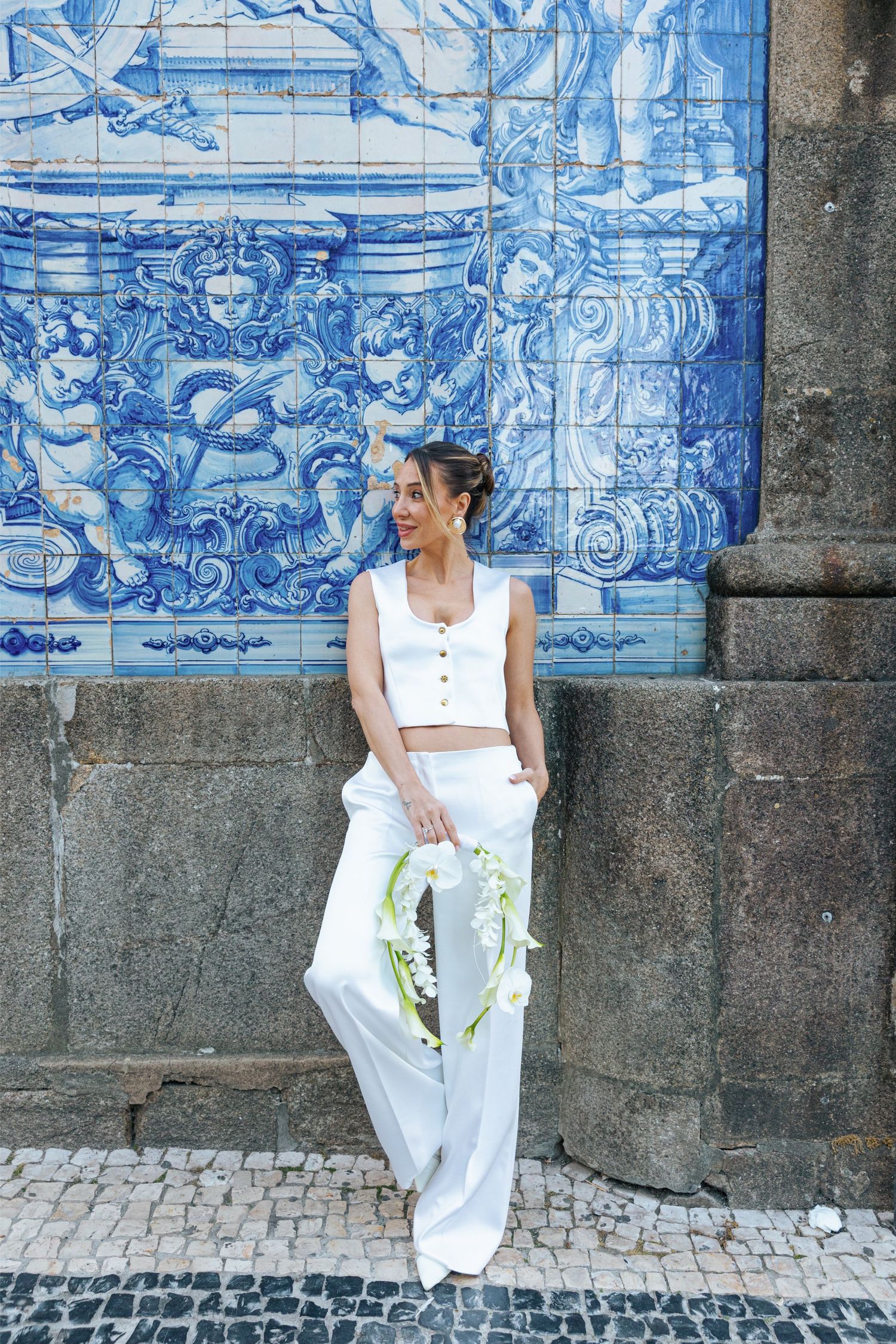 Three connected photos of someone in white clothing sitting against a blue and white Portuguese azulejo tile wall.