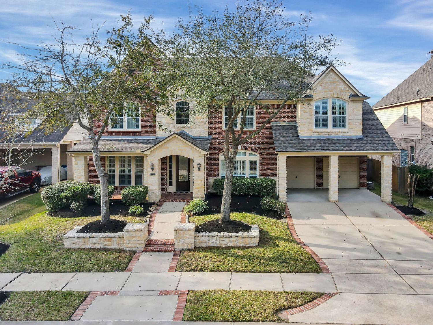 Modern single-story brick home with manicured lawn and curved driveway under bright blue sky.