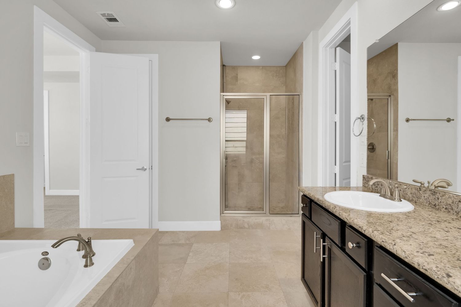 Modern white bathroom interior with granite countertops, dual sinks, and recessed lighting above a large vanity mirror.