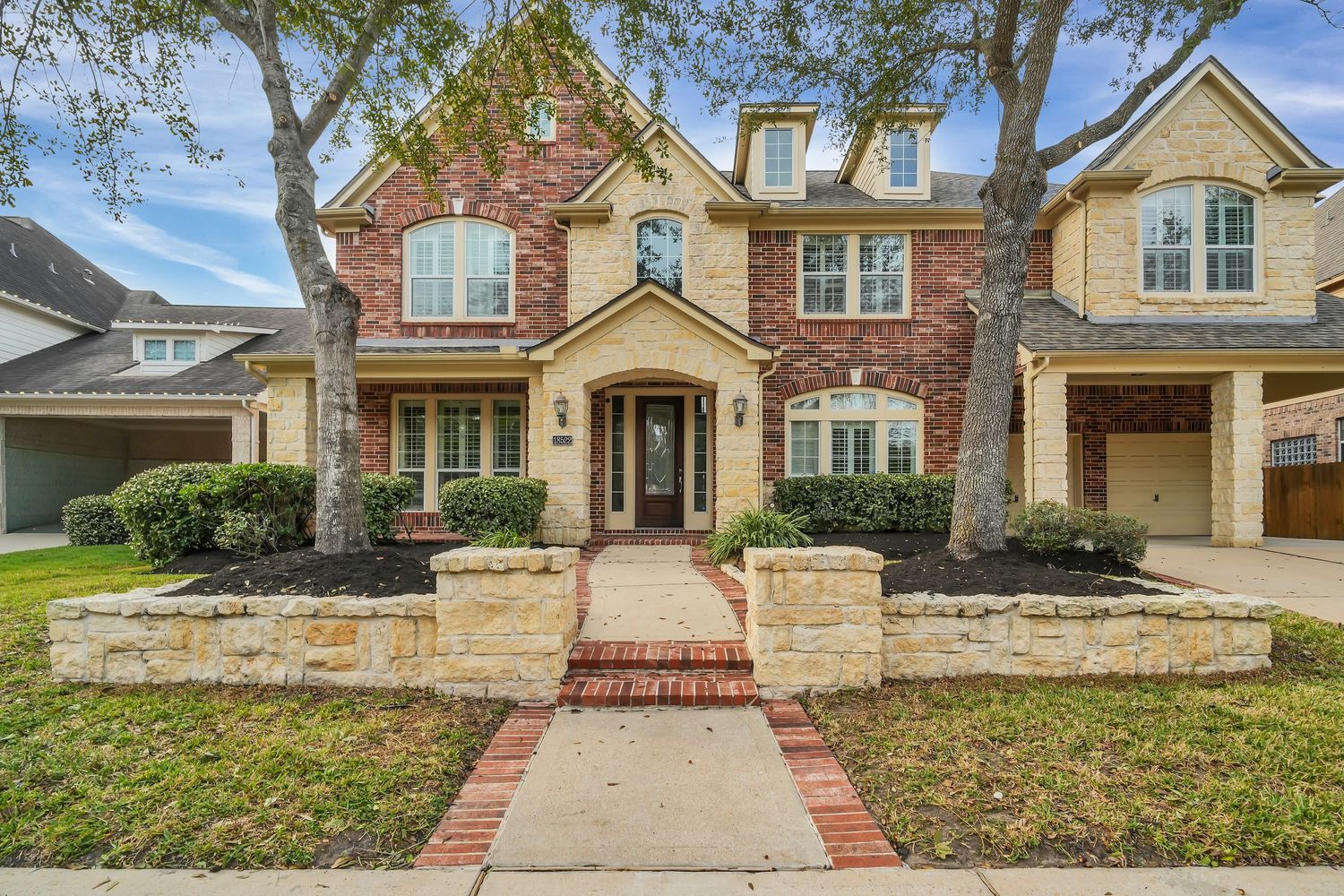 Exterior view of modern brick homes in an upscale suburban neighborhood with manicured lawns and driveways.