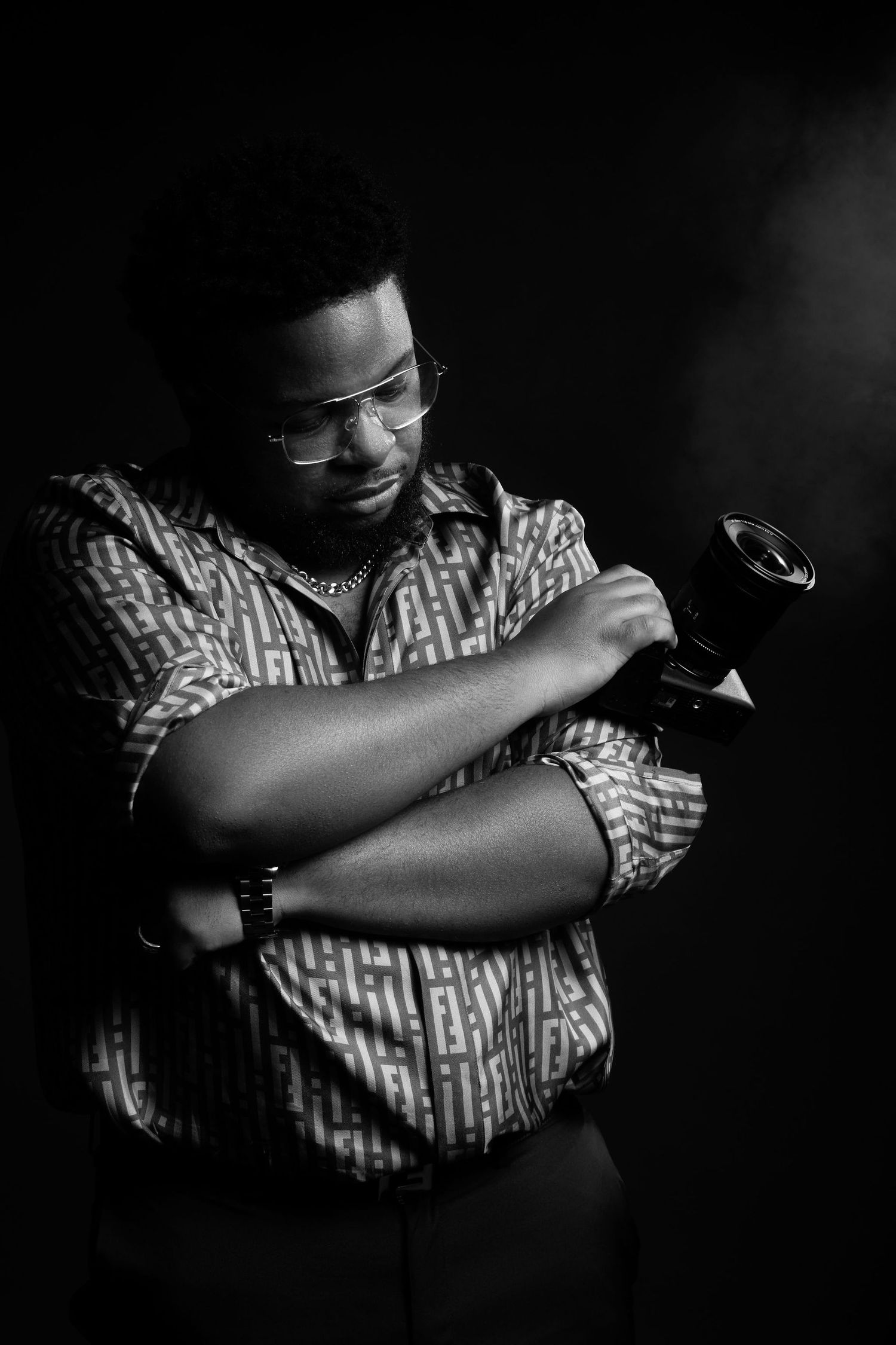Dramatic black and white portrait of a photographer examining their camera in a patterned shirt. Powerrpackmedia Houston Texas