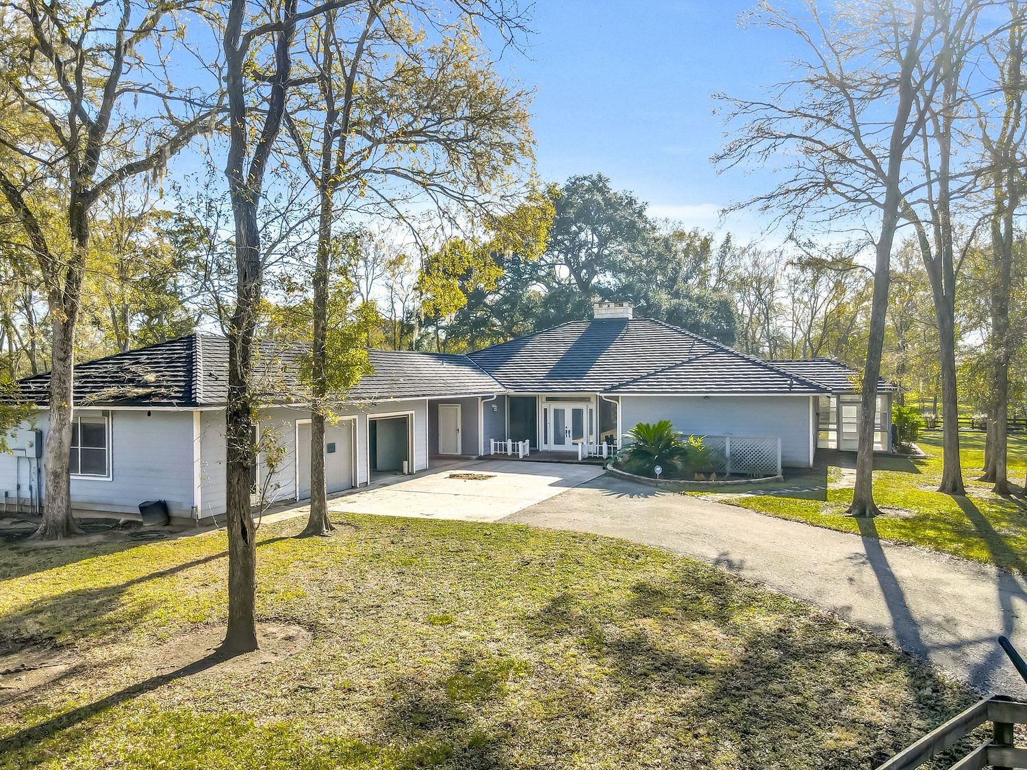 Scenic backyard view of a residential property with mature trees and gentle slopes in autumn sunlight.
