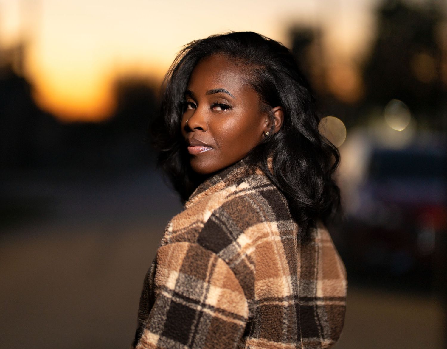 Portrait of person in plaid coat during golden hour sunset with soft bokeh background. Powerrpackmedia Houston Texas