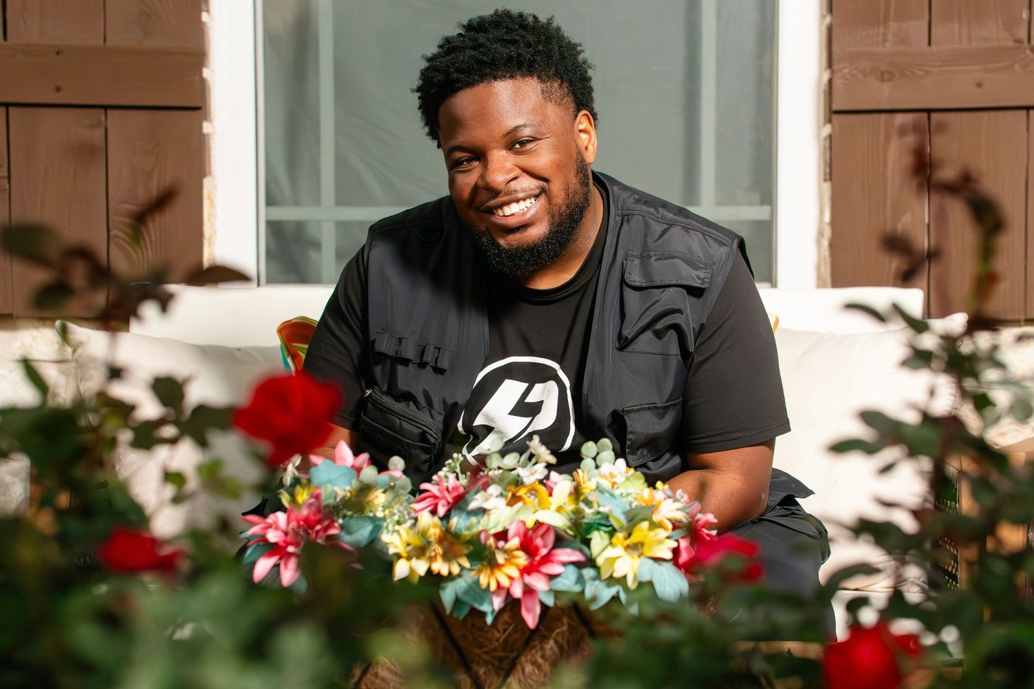 Person smiling while arranging colorful floral bouquets at a wooden table with holiday decorations in the background.