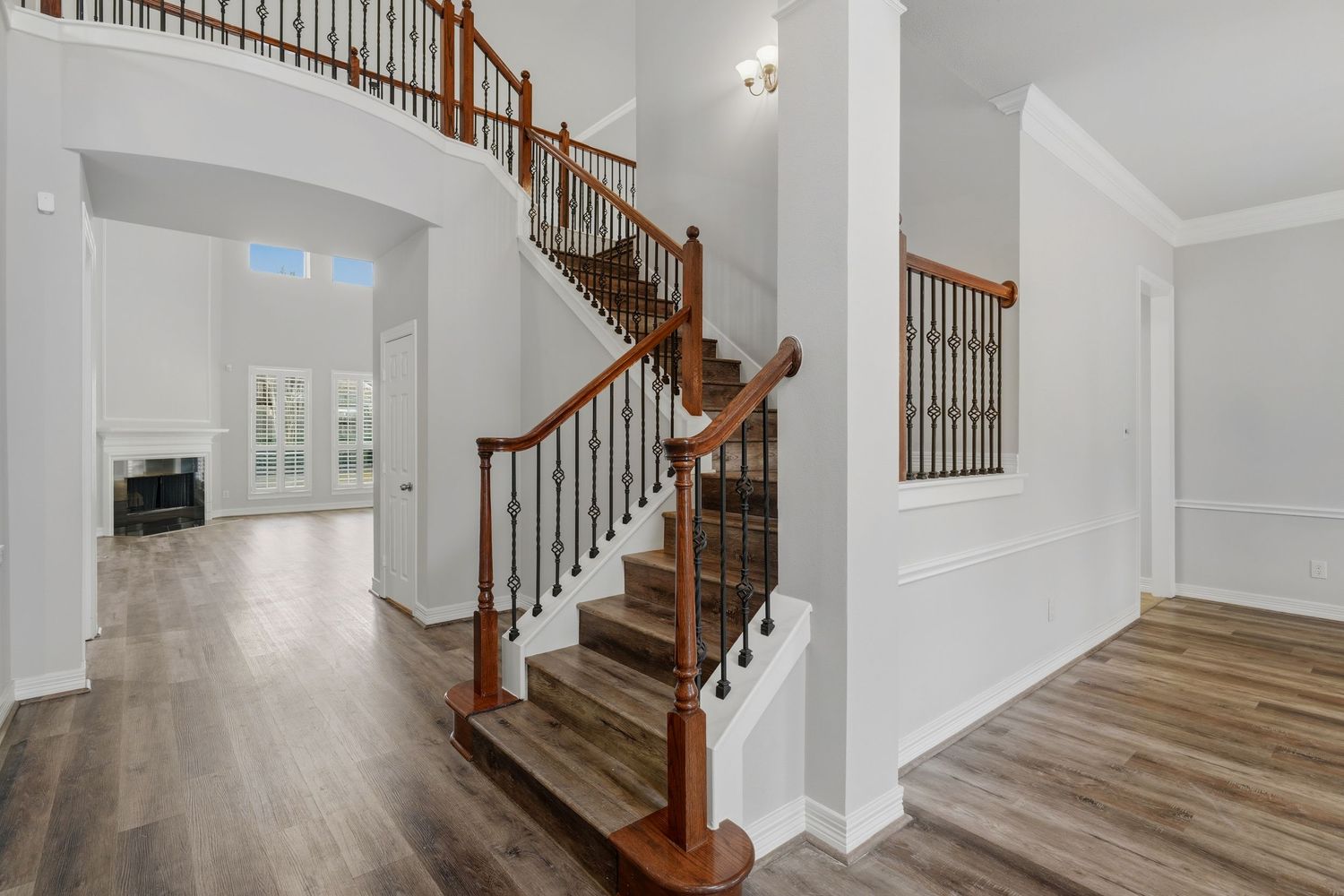 Elegant staircase with white walls, dark wood handrails and hardwood flooring in a modern home interior.