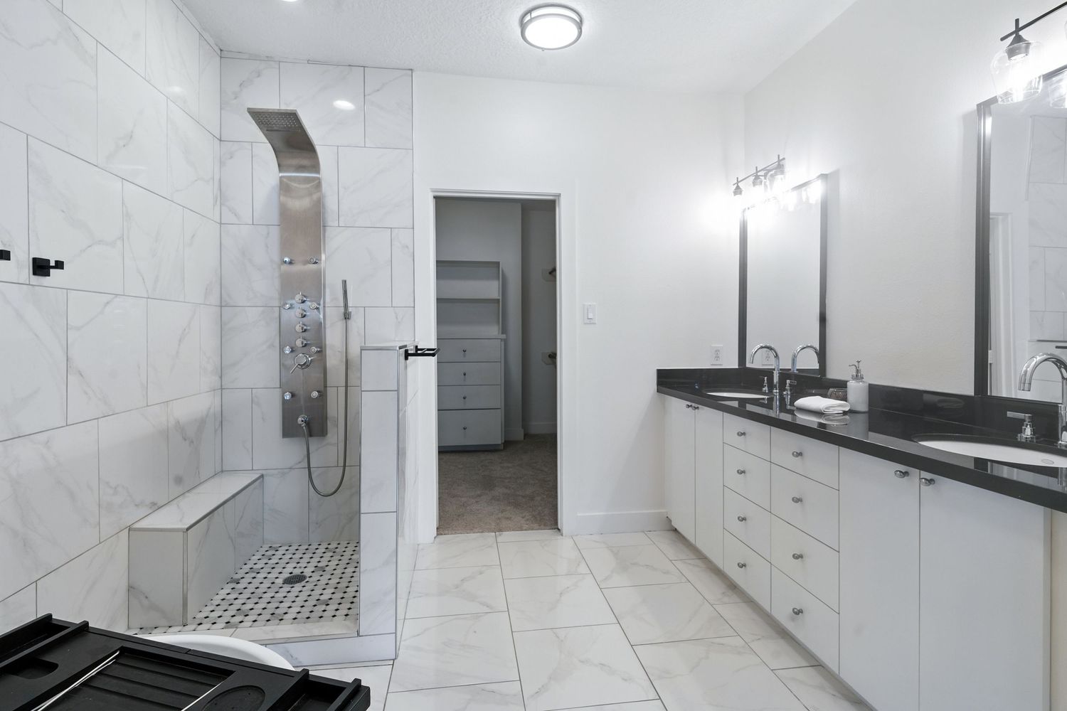 Modern white bathroom interior with marble tiles, built-in cabinets, and sleek minimalist fixtures throughout the space.