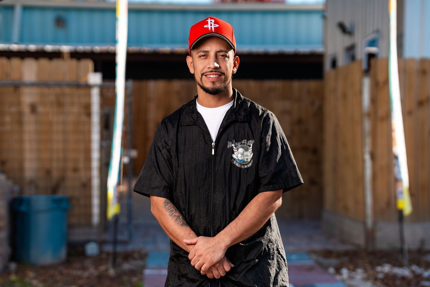 Person in black jacket and red baseball cap stands in front of industrial building. Powerrpackmedia Houston Texas