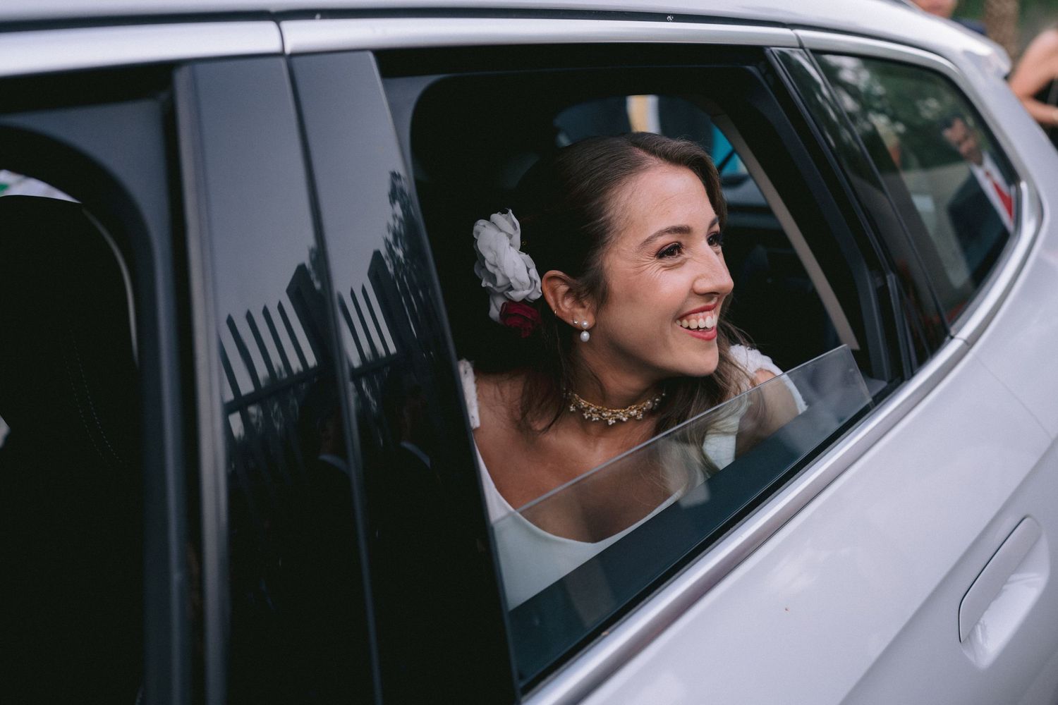 Wedding party members smiling inside a white vehicle.