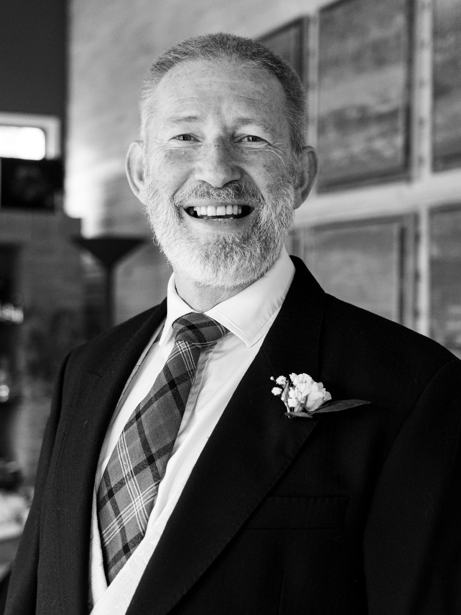 Black and white portrait of a gentleman in formal wedding attire with a boutonniere.