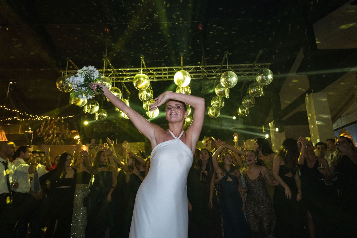 Wedding reception dance party with colorful lighting and a crowded dance floor.