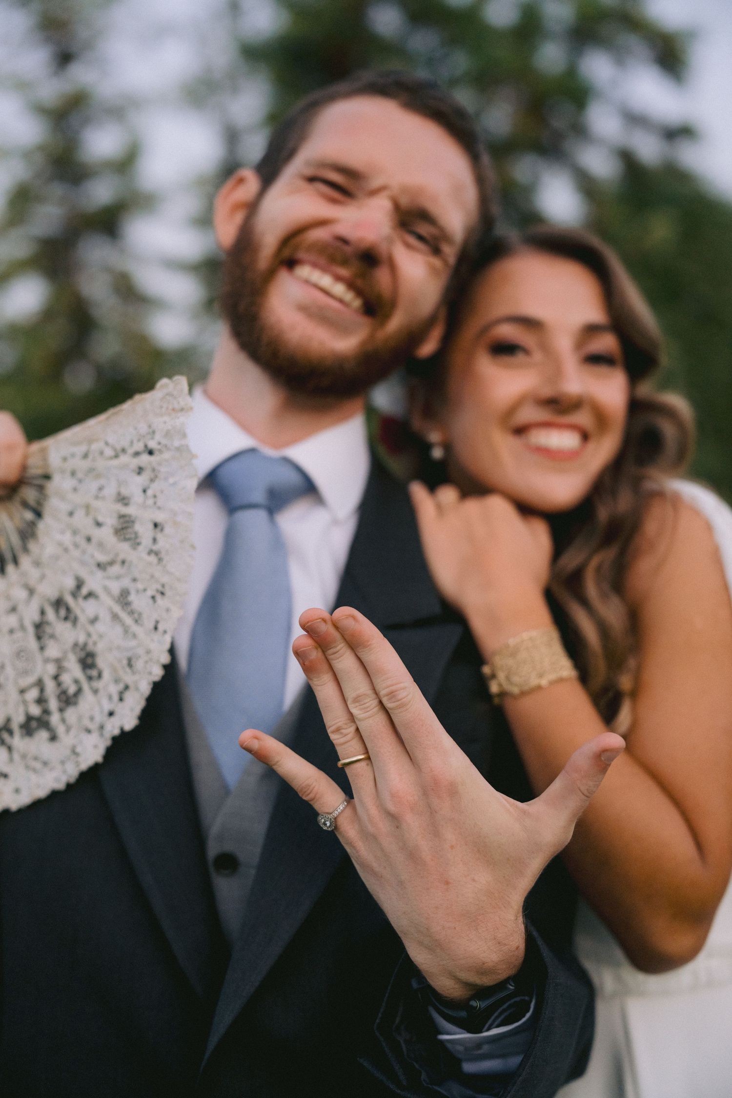 Close-up shot of wedding rings and joyful expressions during outdoor celebration.