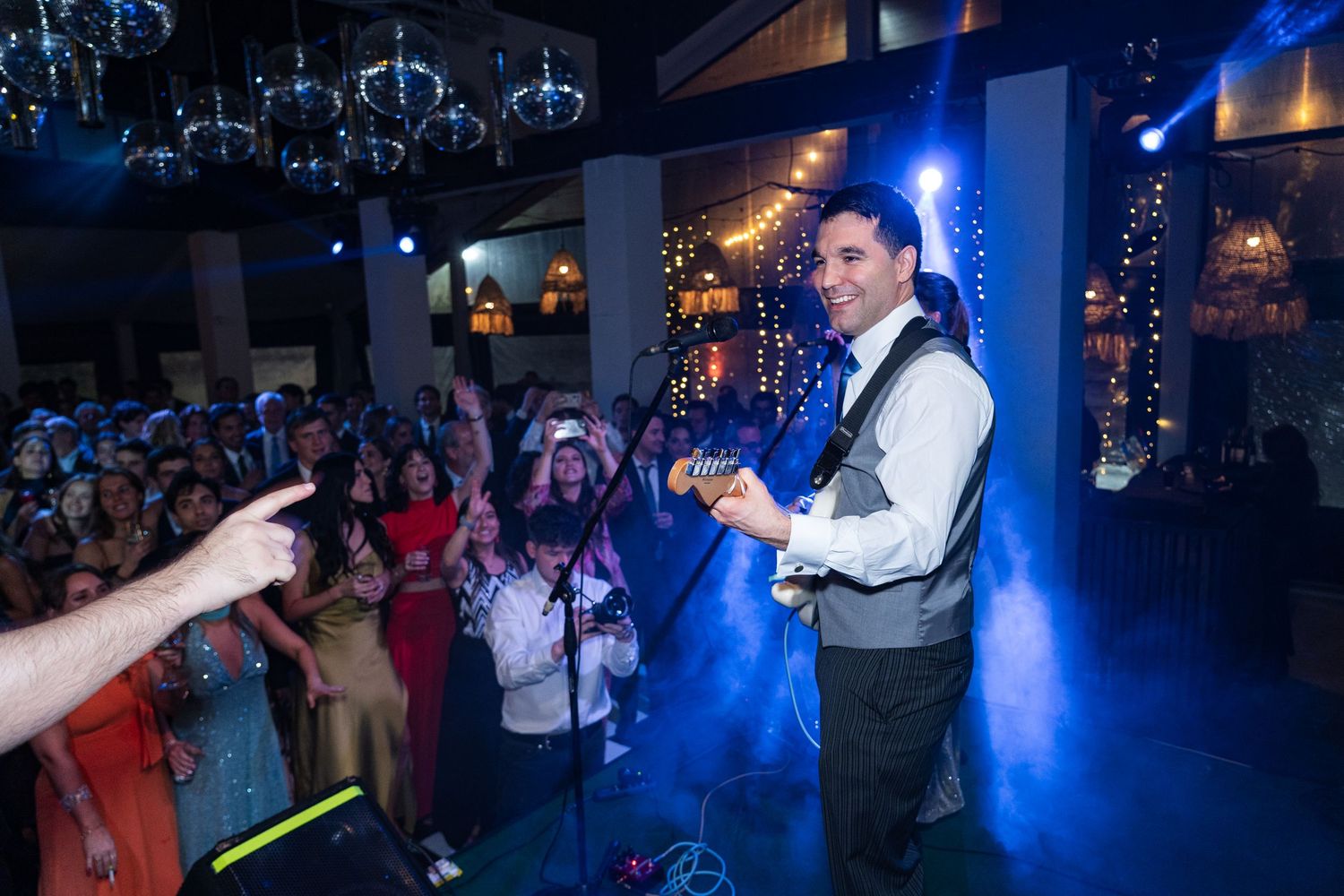Wedding reception performance with dramatic blue lighting and dancing guests.