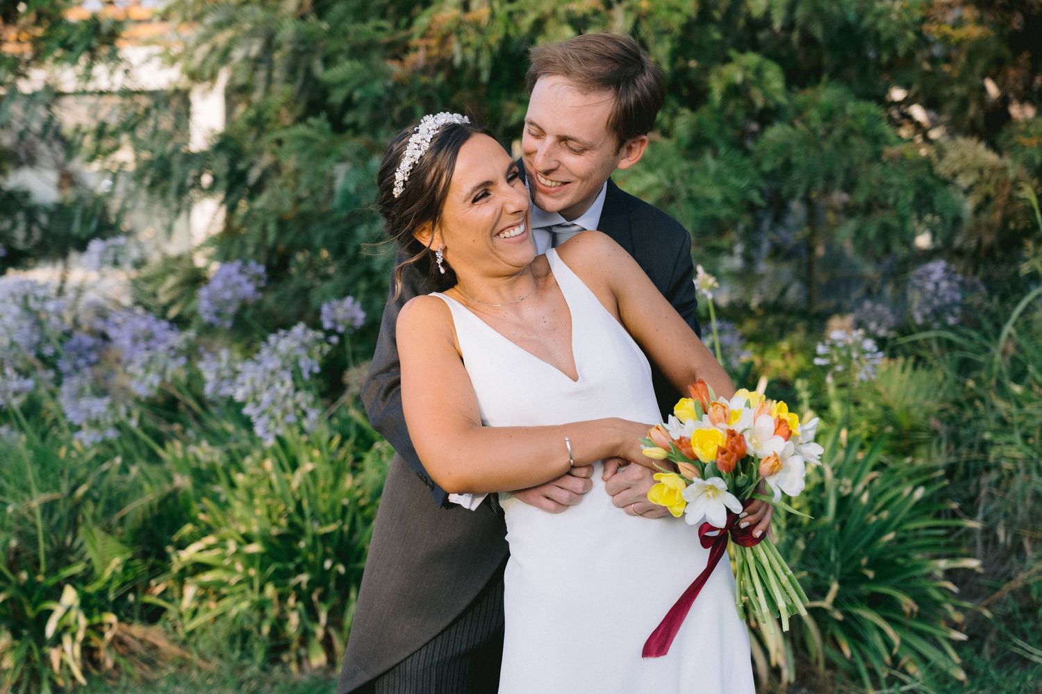 Newlyweds sharing intimate moment in garden with colorful bouquet.