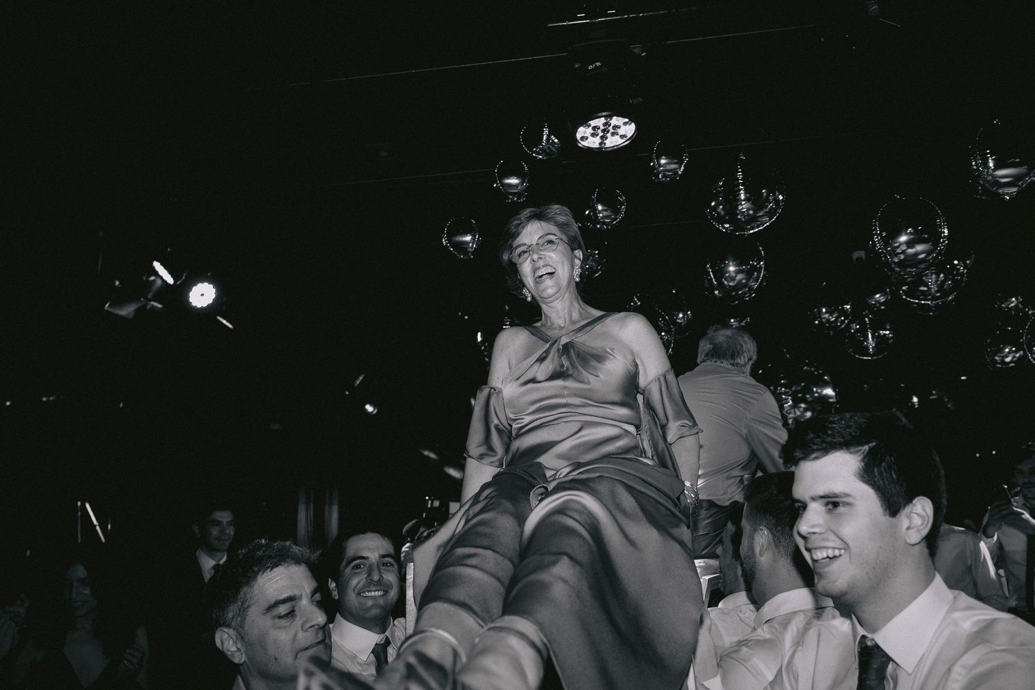 A crowded dance floor filled with party guests celebrating under dim lighting.