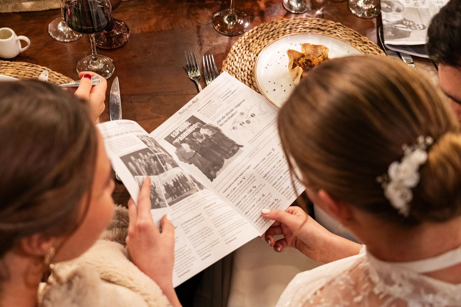 Guests reading menus or programs at wooden tables during an event.