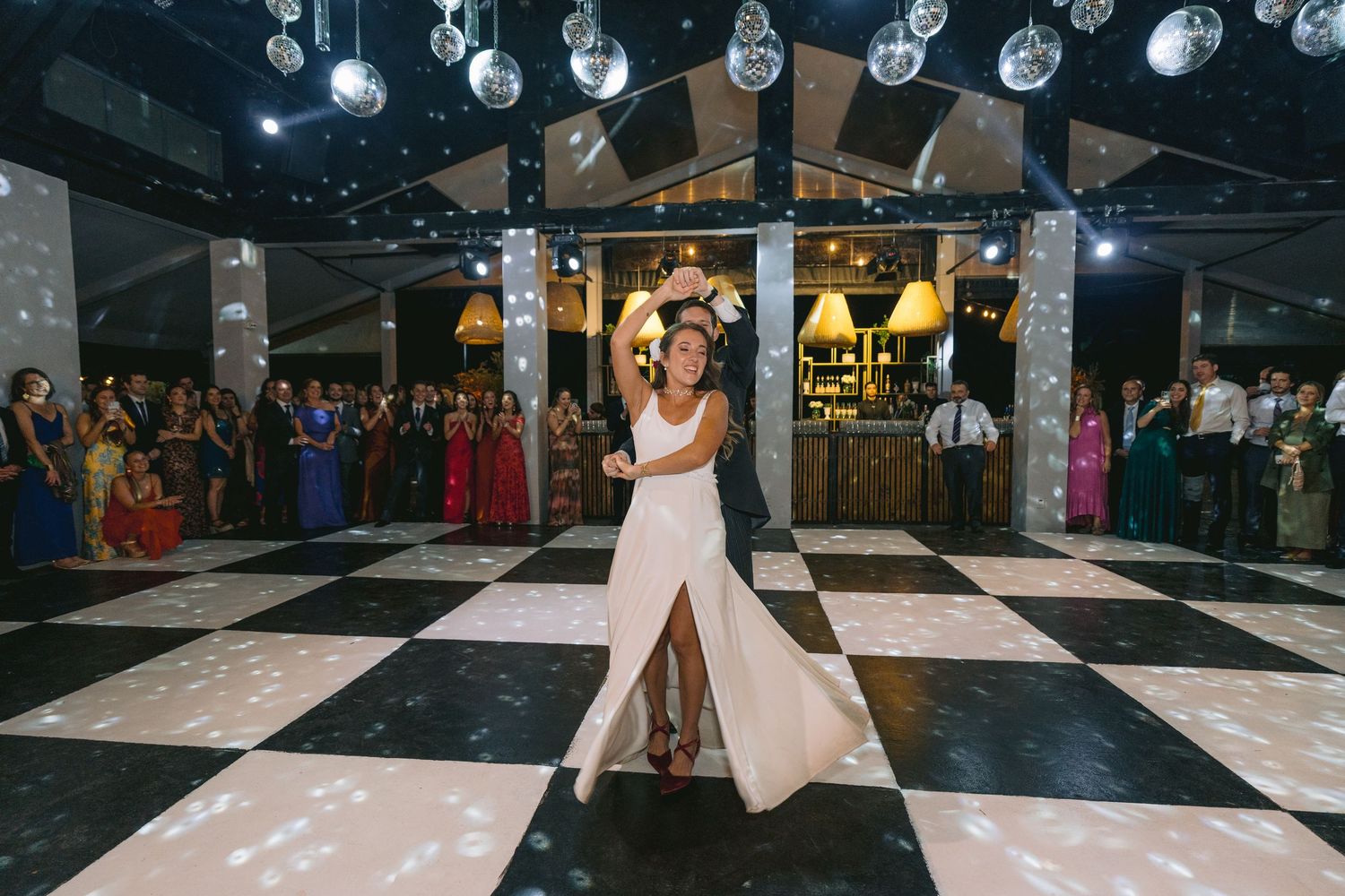 Reception venue with hanging crystal ball decorations above a black and white checkered dance floor.